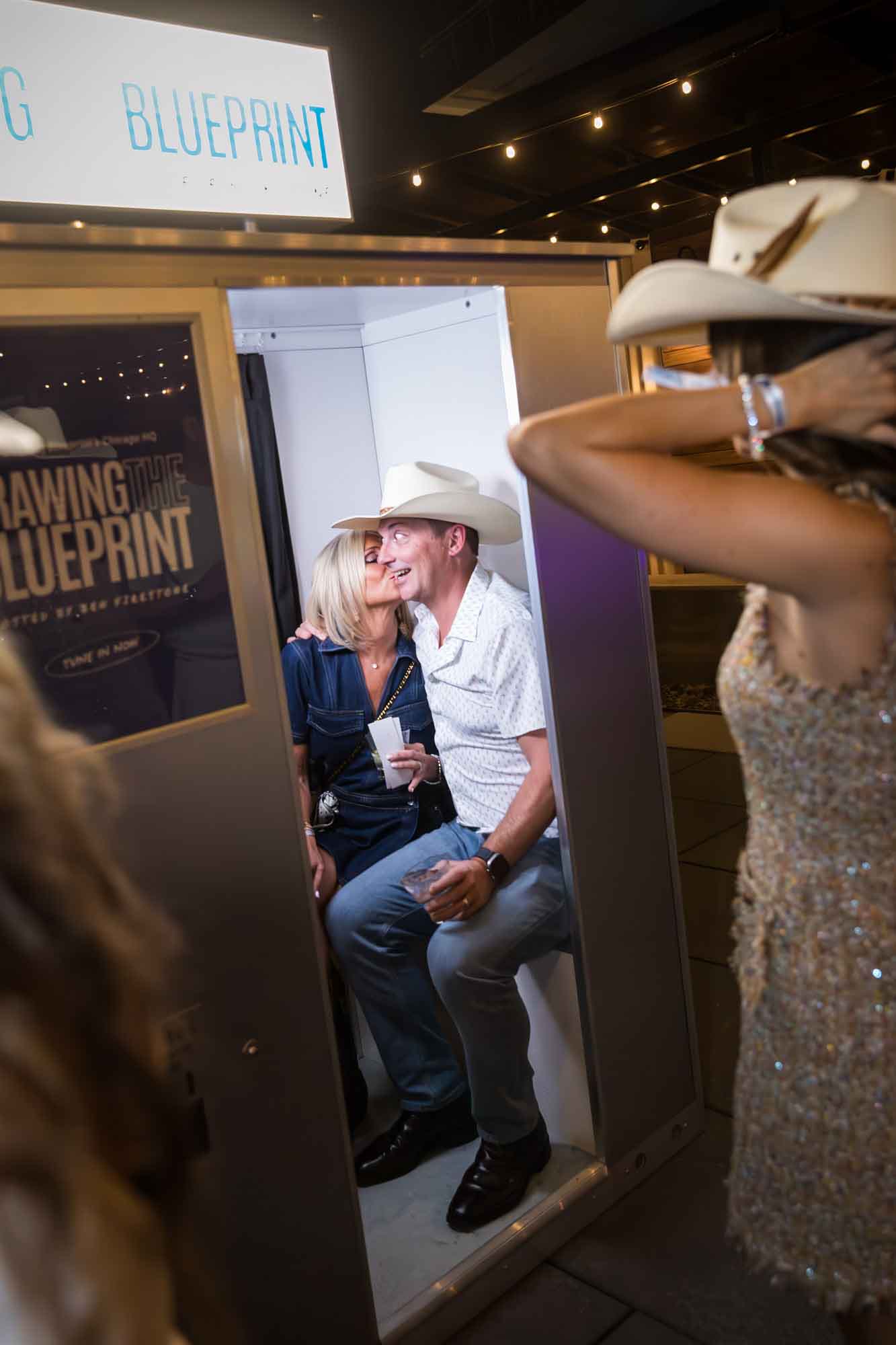 Woman kissing man wearing white cowboy hat in photo booth during a Hotel Van Zandt corporate event