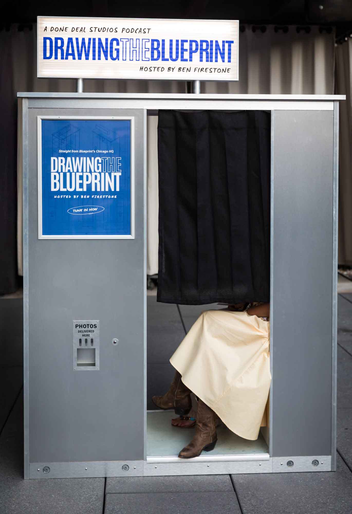 Photo booth with woman seated inside showing yellow skirt and brown cowboy boots peeking out during a Hotel Van Zandt corporate event