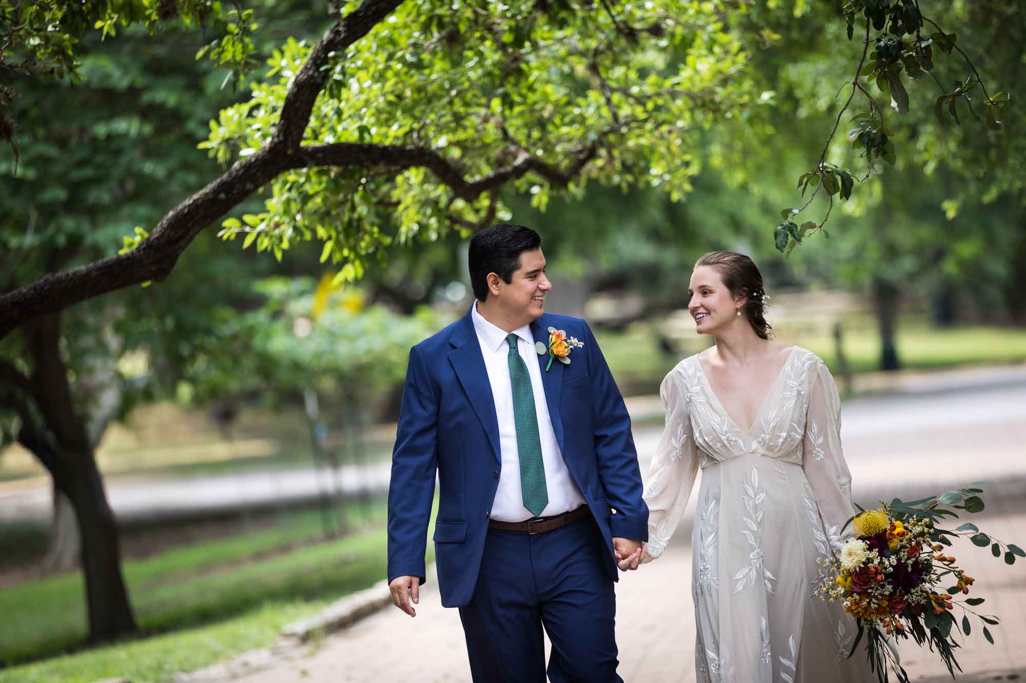Bride and groom walking under trees in Landa Park for an article on outdoor wedding tips