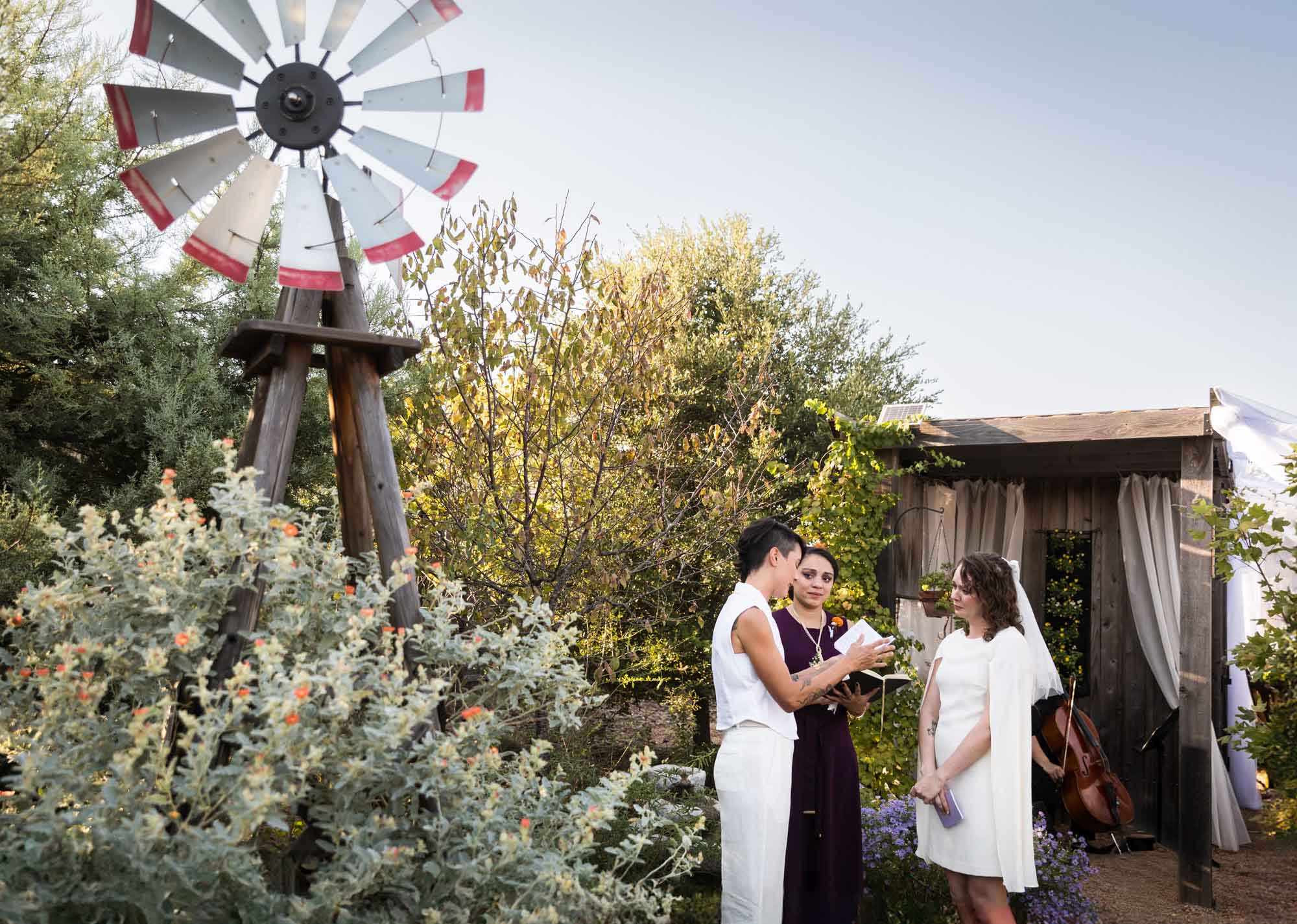 Bride and bride exchanging vows with windmill in background for an article on outdoor wedding tips