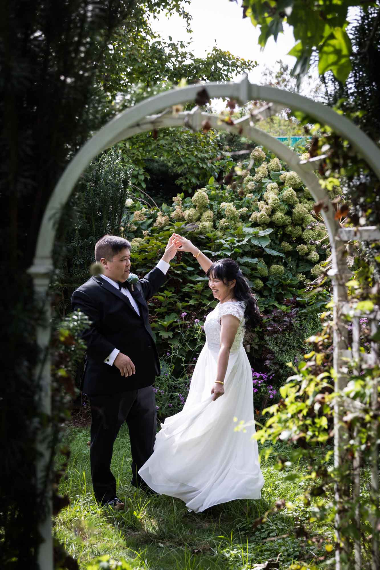 Bride and groom dancing as viewed through lattice arch in garden for an article on outdoor wedding tips