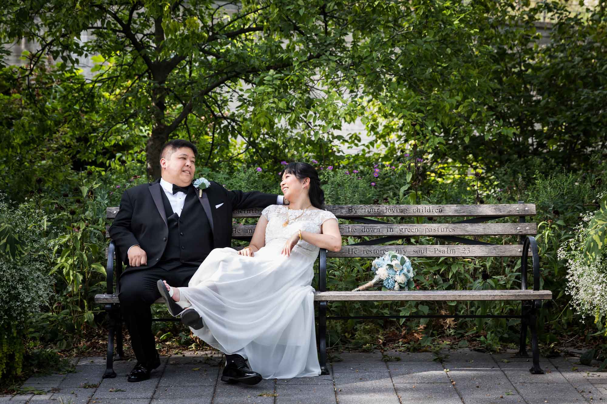 Bride and groom sitting together on bench with flower bouquet on bench for an article on outdoor wedding tips