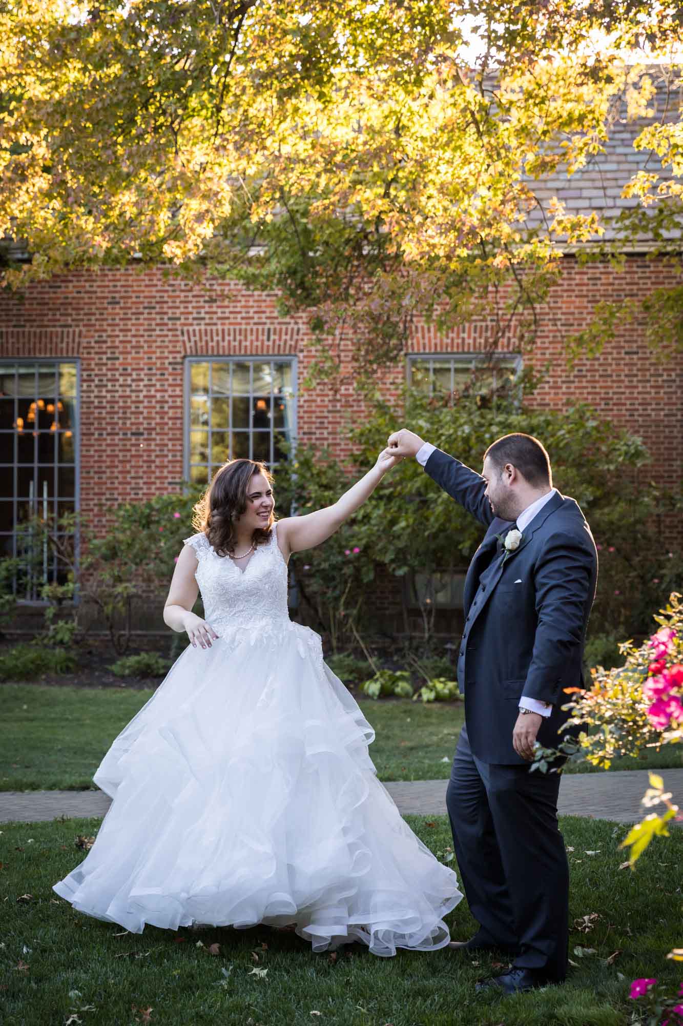 Groom holding bride's hand dancing in garden for an article on outdoor wedding tips