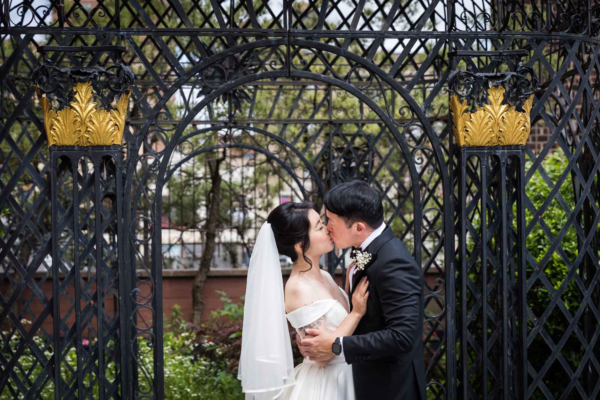Bride and groom kissing in front of black iron gazebo for an article on outdoor wedding tips