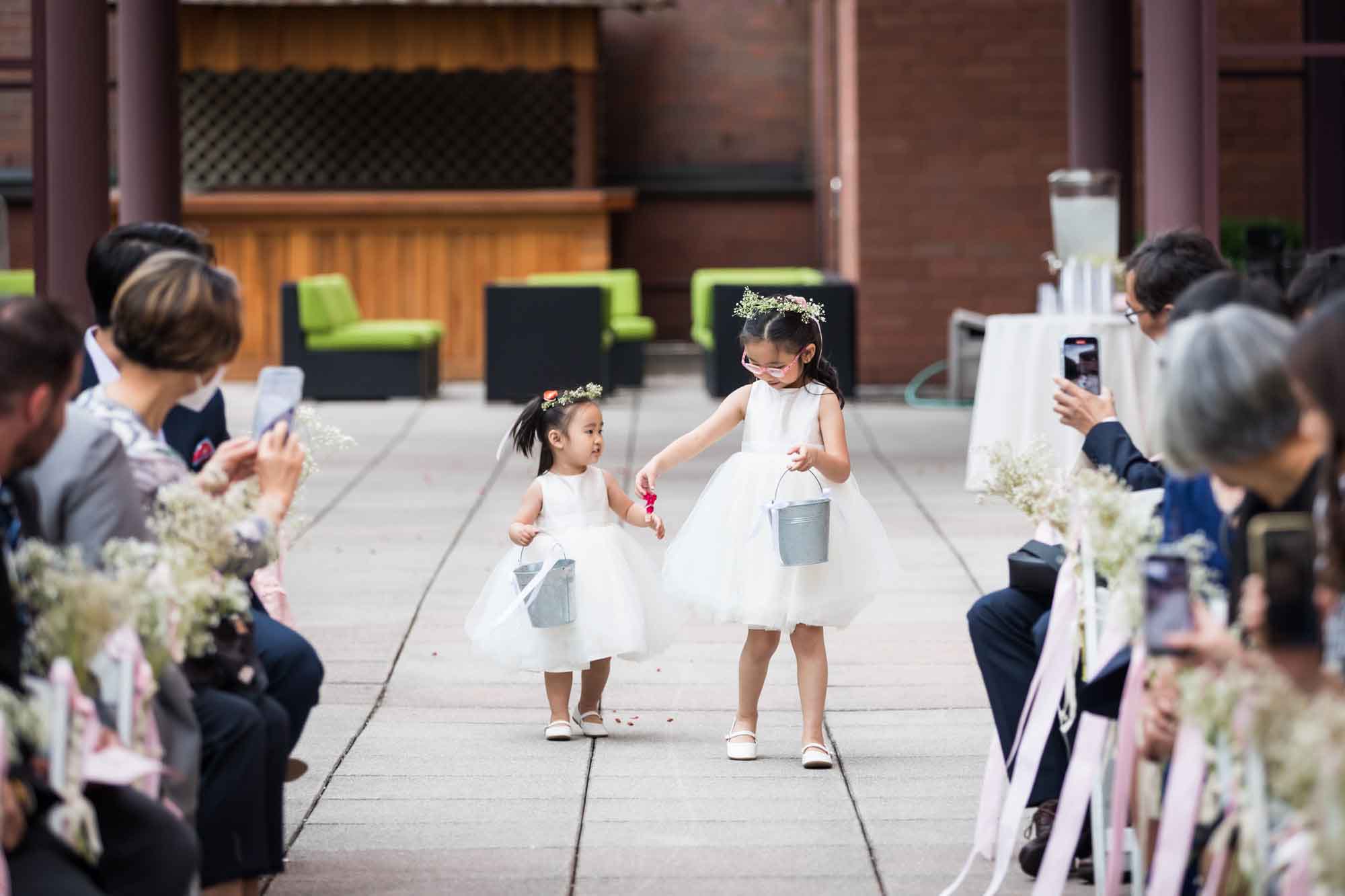 Two little flower girls walking down an aisle in front of guests for an article on outdoor wedding tips