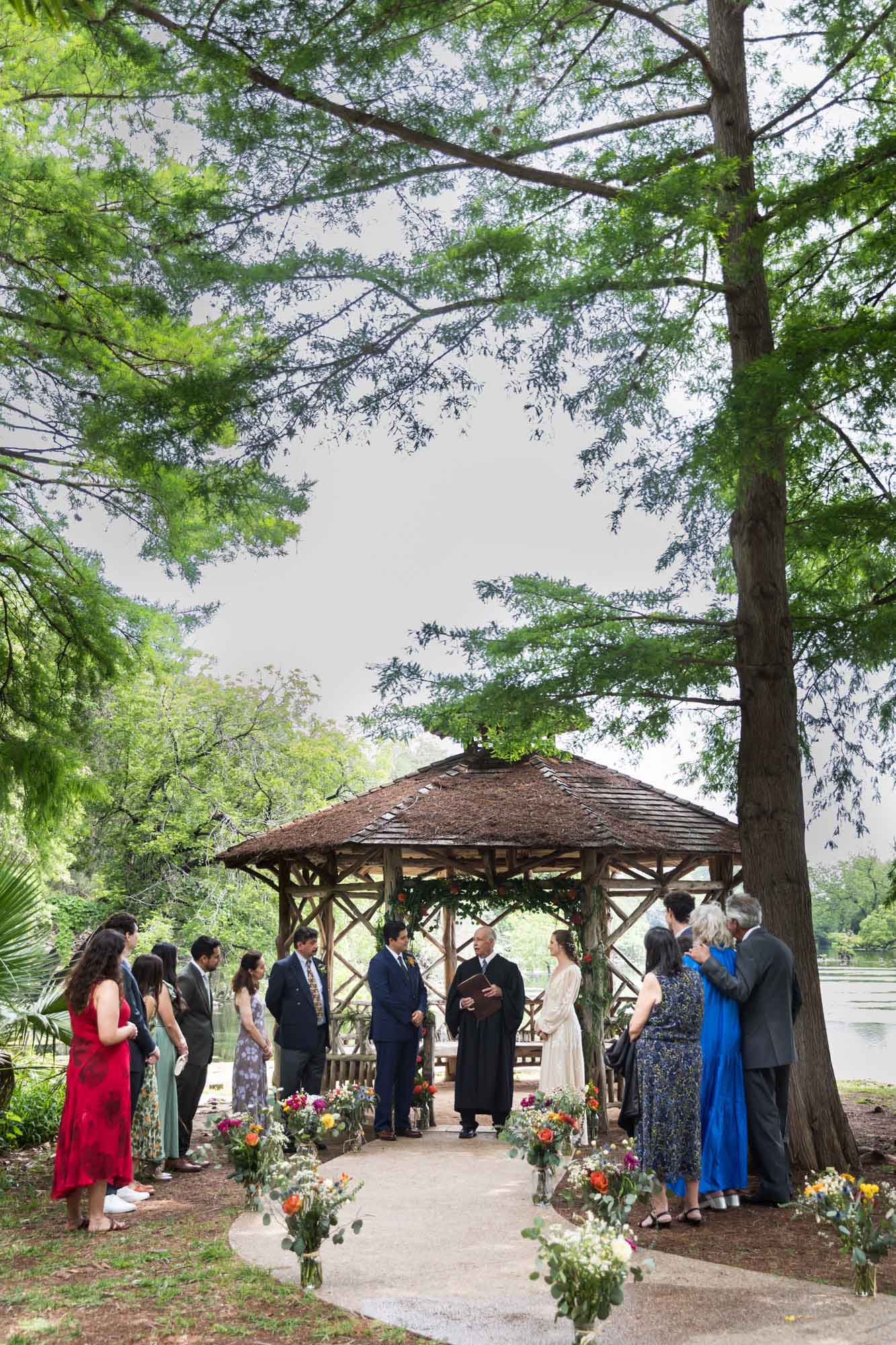 Bride and groom exchanging vows in front of guests at Landa Park Lake gazebo for an article on outdoor wedding tips