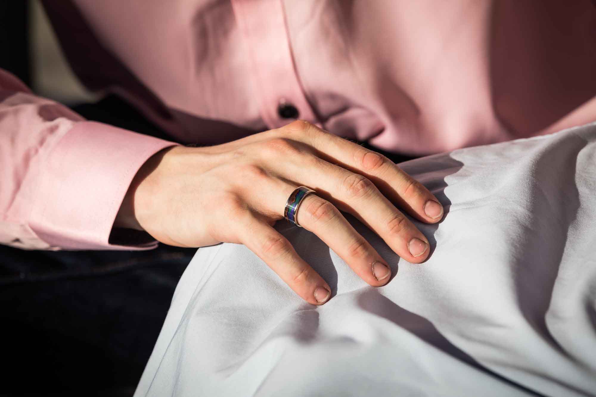 Close up of man's hand showing engagement ring with multi-colored stone