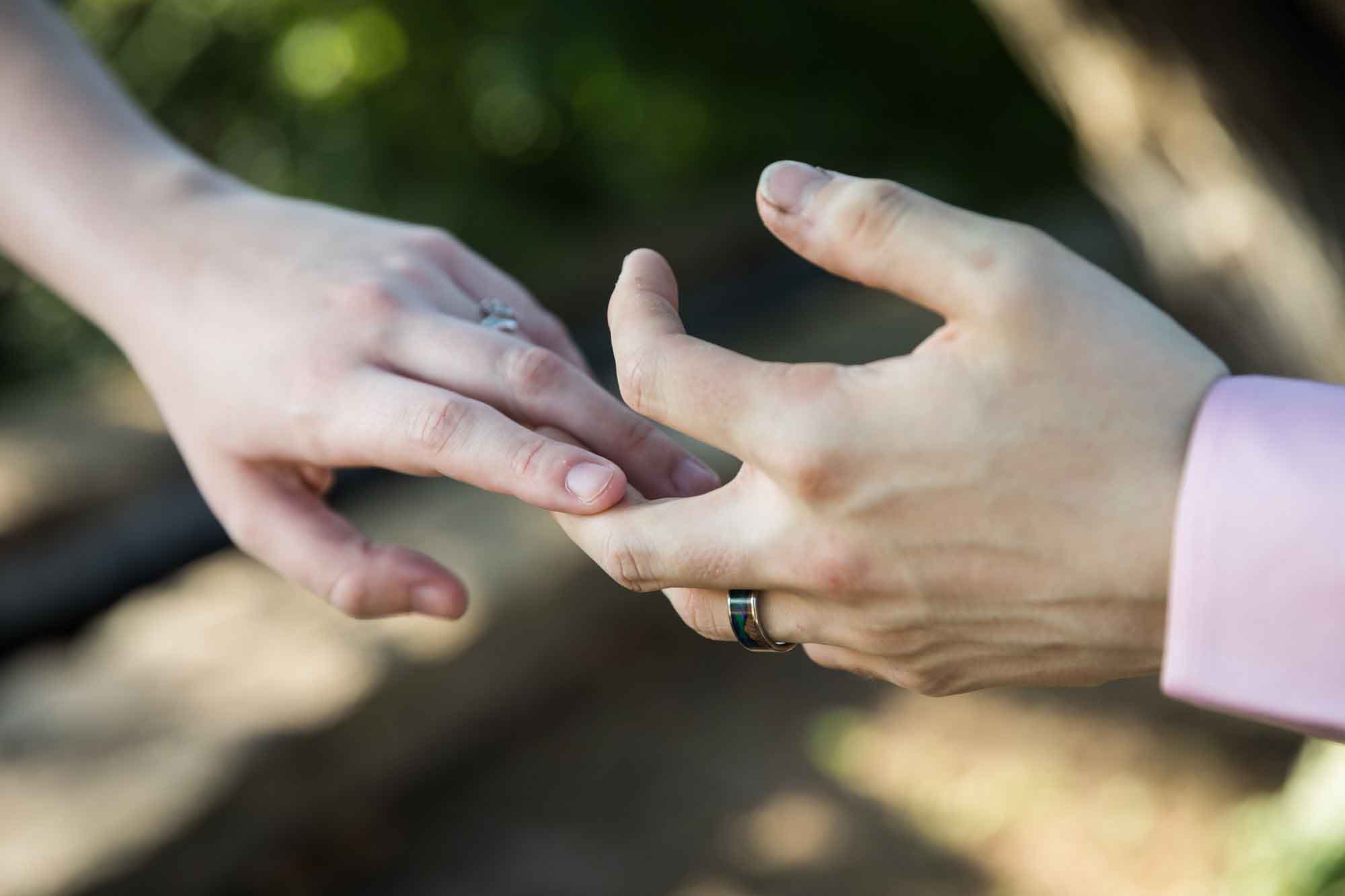 Close up of man and woman touching hands at the fingertips showing engagement rings