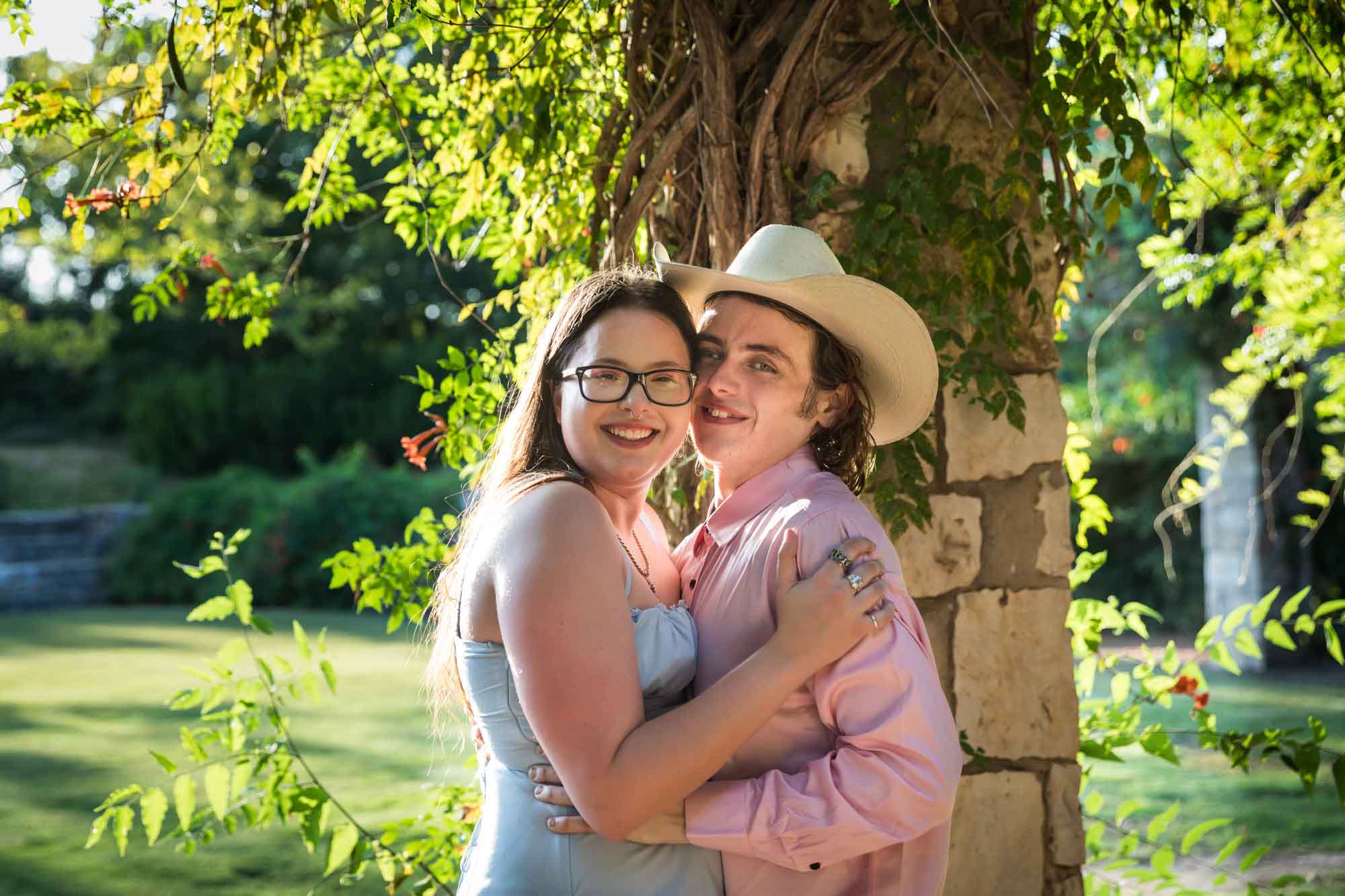 San Antonio Botanical Garden engagement photos of couple hugging in front of stone column at the Amphitheater