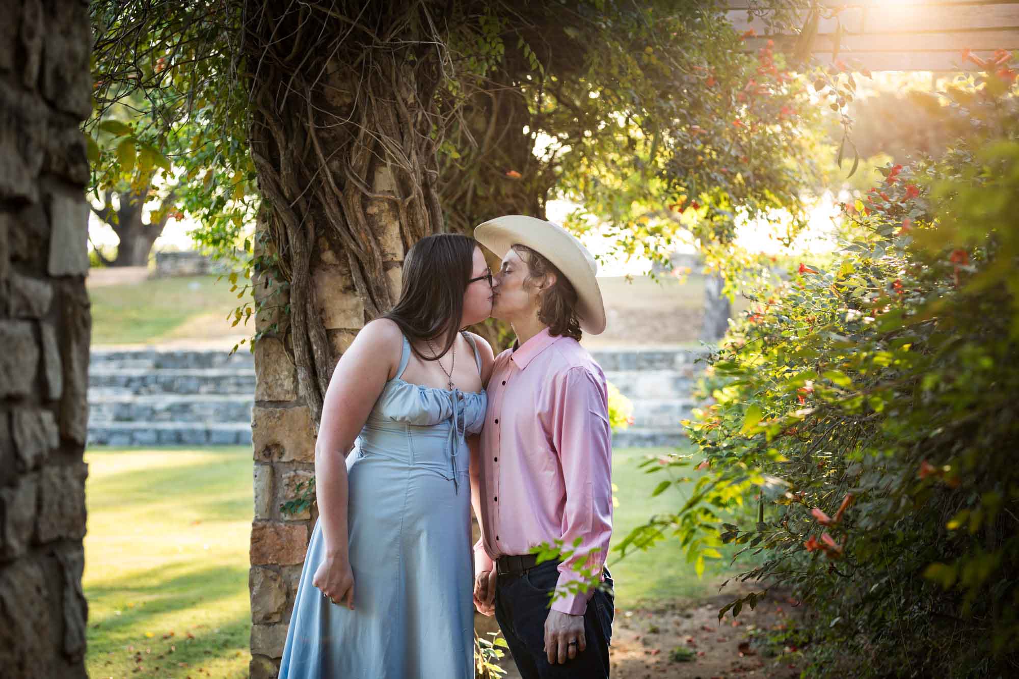 San Antonio Botanical Garden engagement photos of couple kissing in front of vines at the Amphitheater