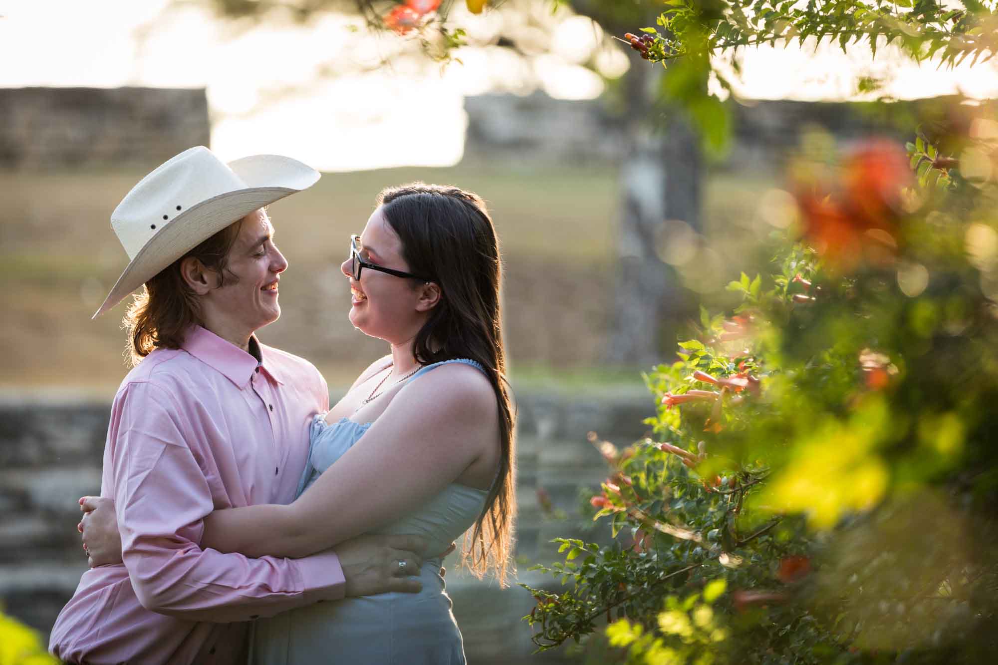 San Antonio Botanical Garden engagement photos of couple hugging in front of vines at the Amphitheater