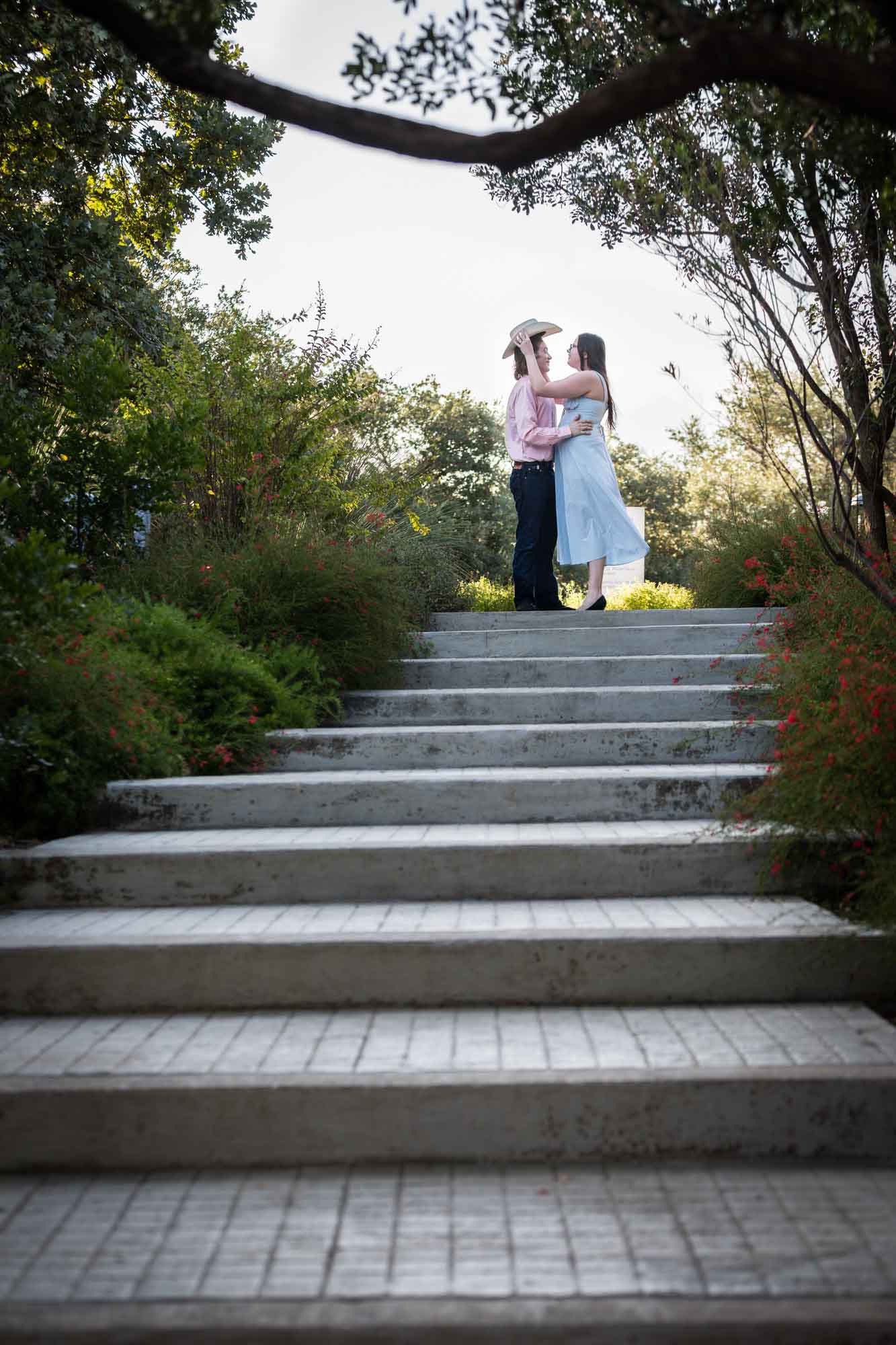 San Antonio Botanical Garden engagement photos of couple hugging at top of staircase