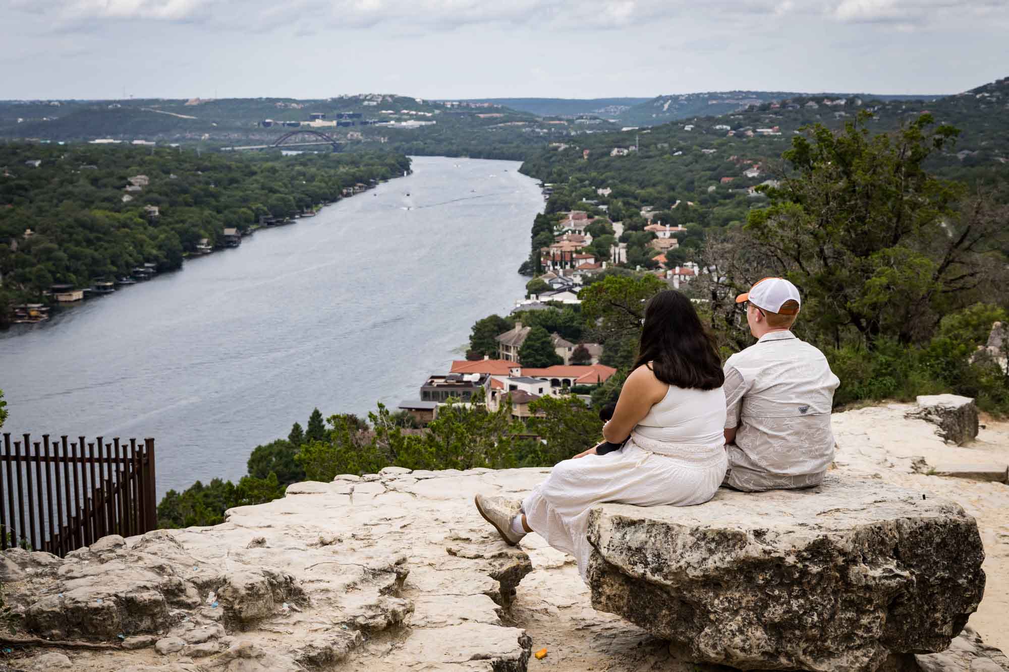 Couple sitting on a stone bench watching the Colorado River at Mount Bonnell for an article on the best places to propose in Austin
