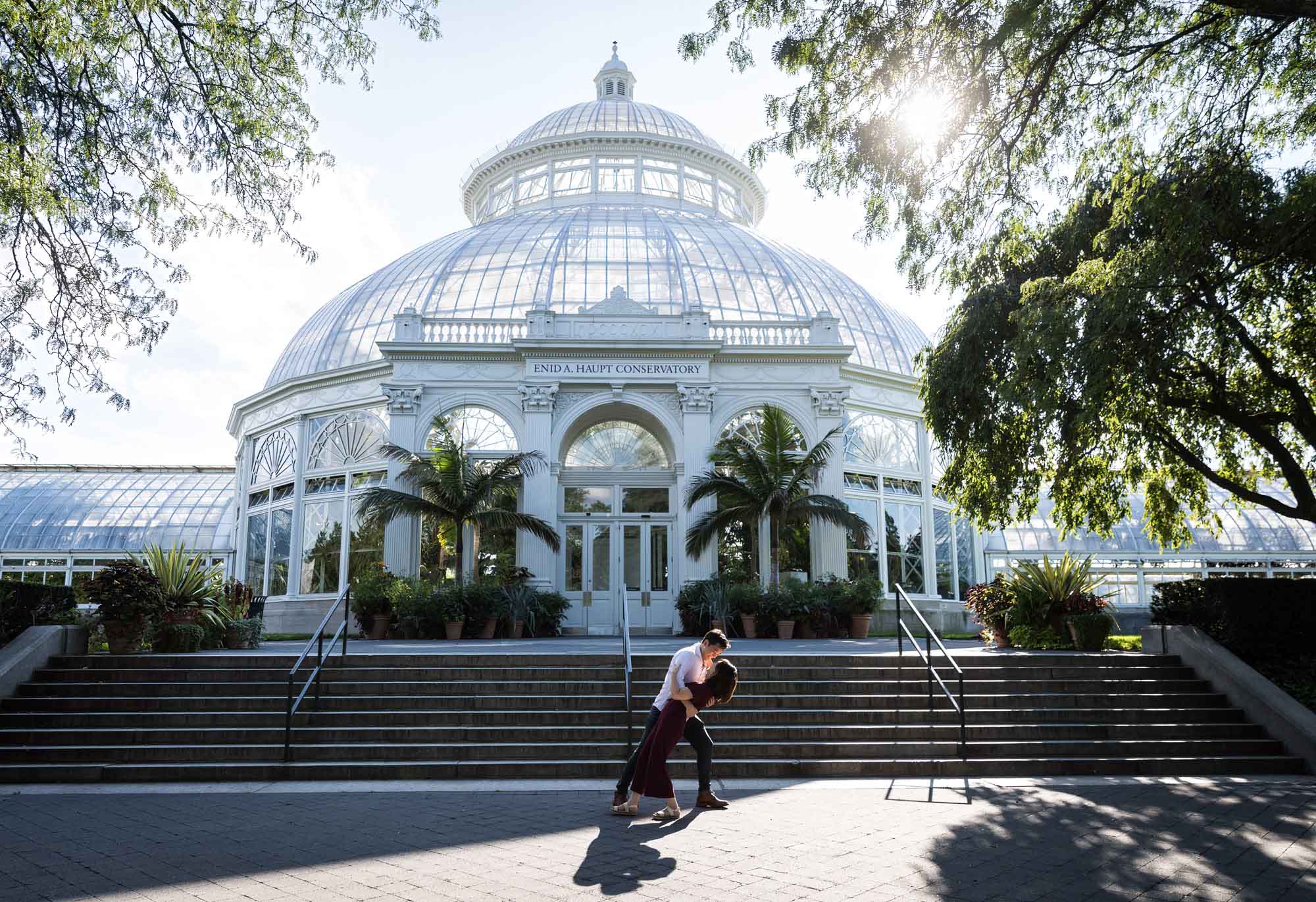 Couple dancing in front of a glass conservatory at the Brooklyn Botanical Garden for an article on the best places to propose in Austin