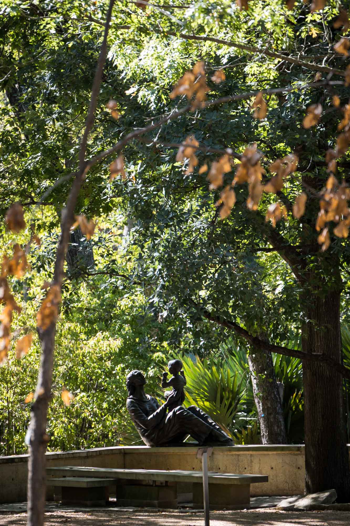 Sculpture of woman holding up child under trees at the Umlauf Sculpture Garden for an article on the best places to propose in Austin