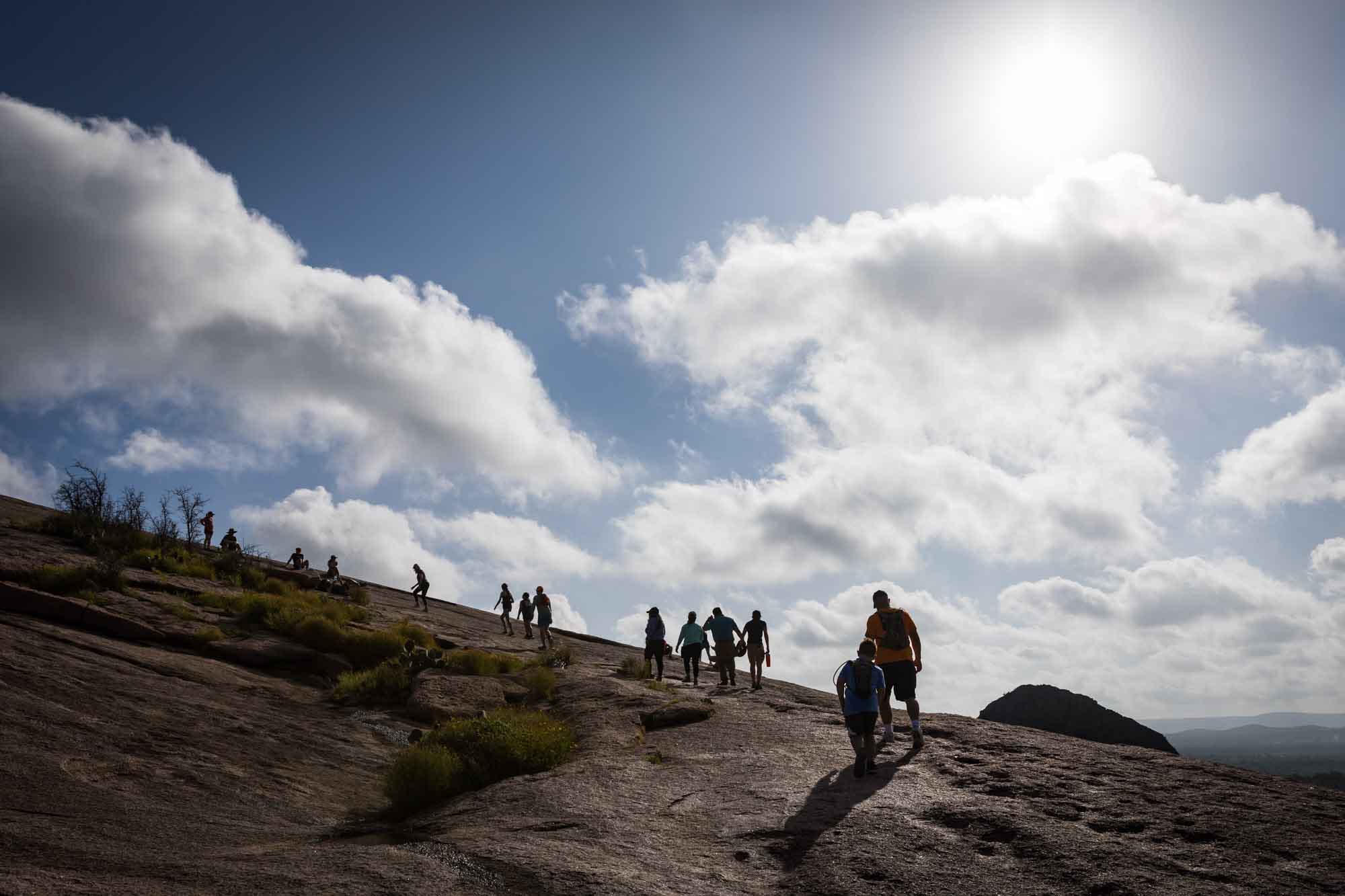 Backlit photo of people hiking up Enchanted Rock for an article on the best places to propose in Austin