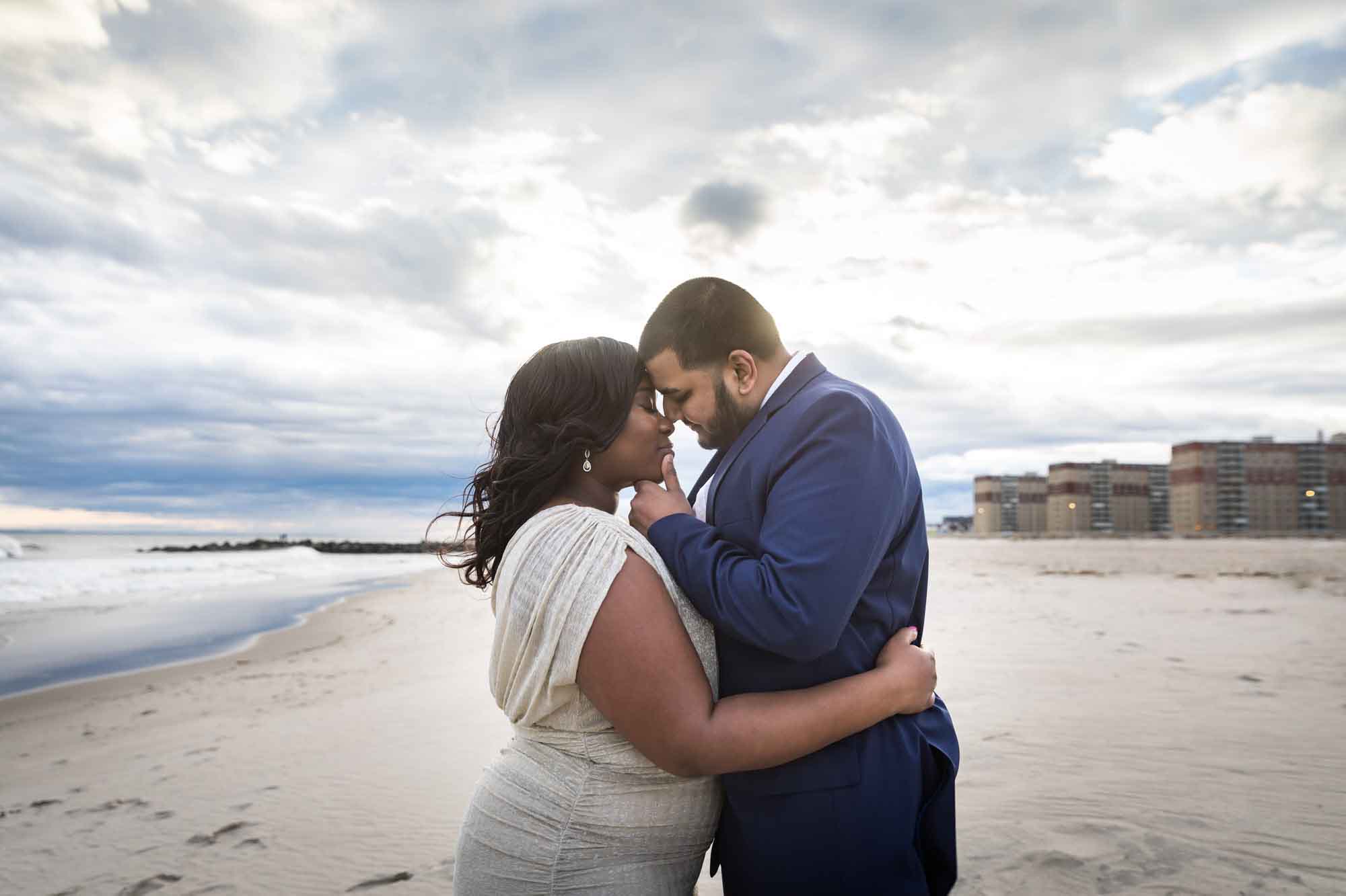 Couple hugging on the beach with clouds overhead for an article on the best places to propose in Austin