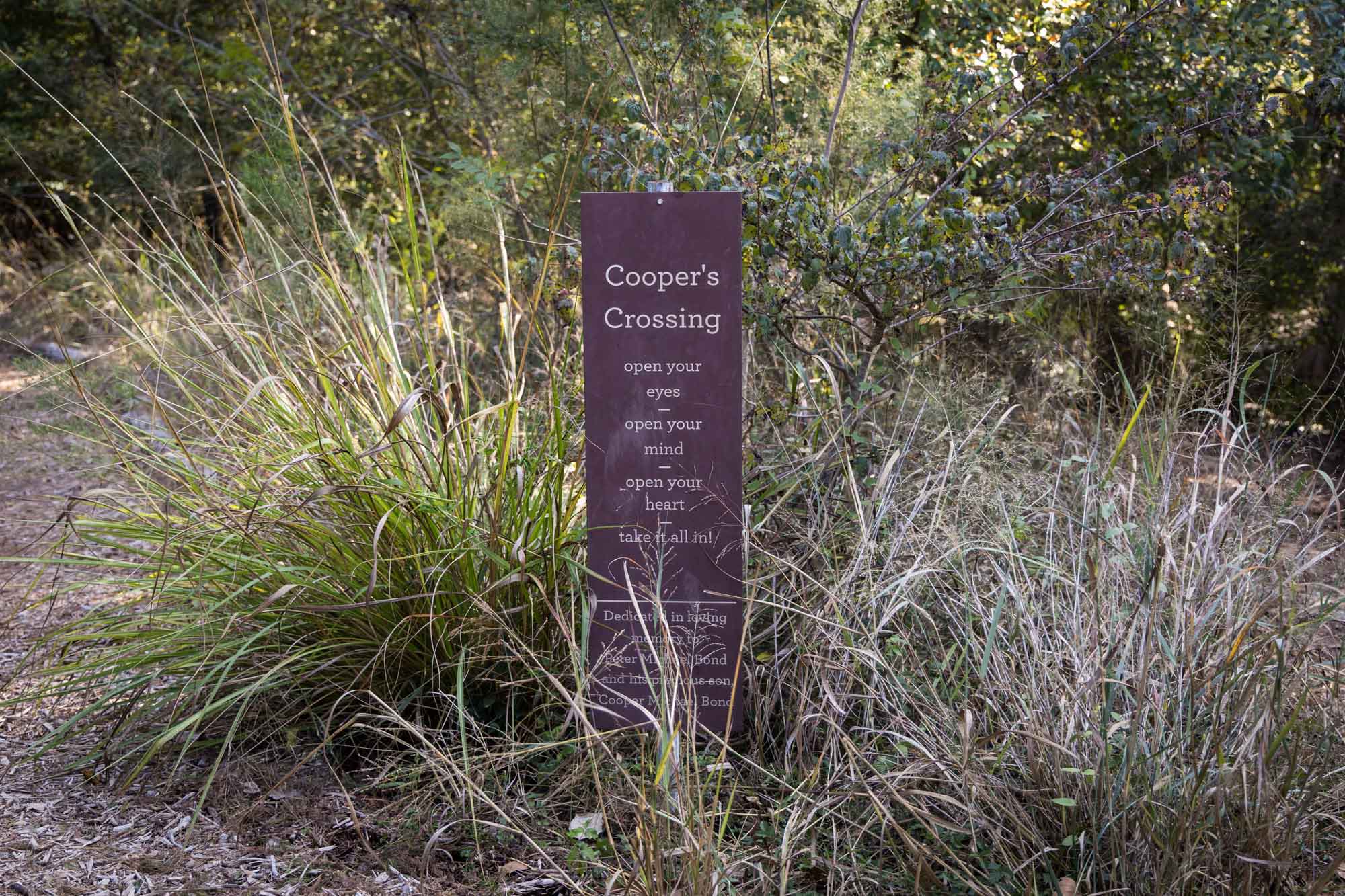 Rusted sign for Cooper's Crossing surrounded by grasses for an article on Cibolo Nature Center surprise proposal tips