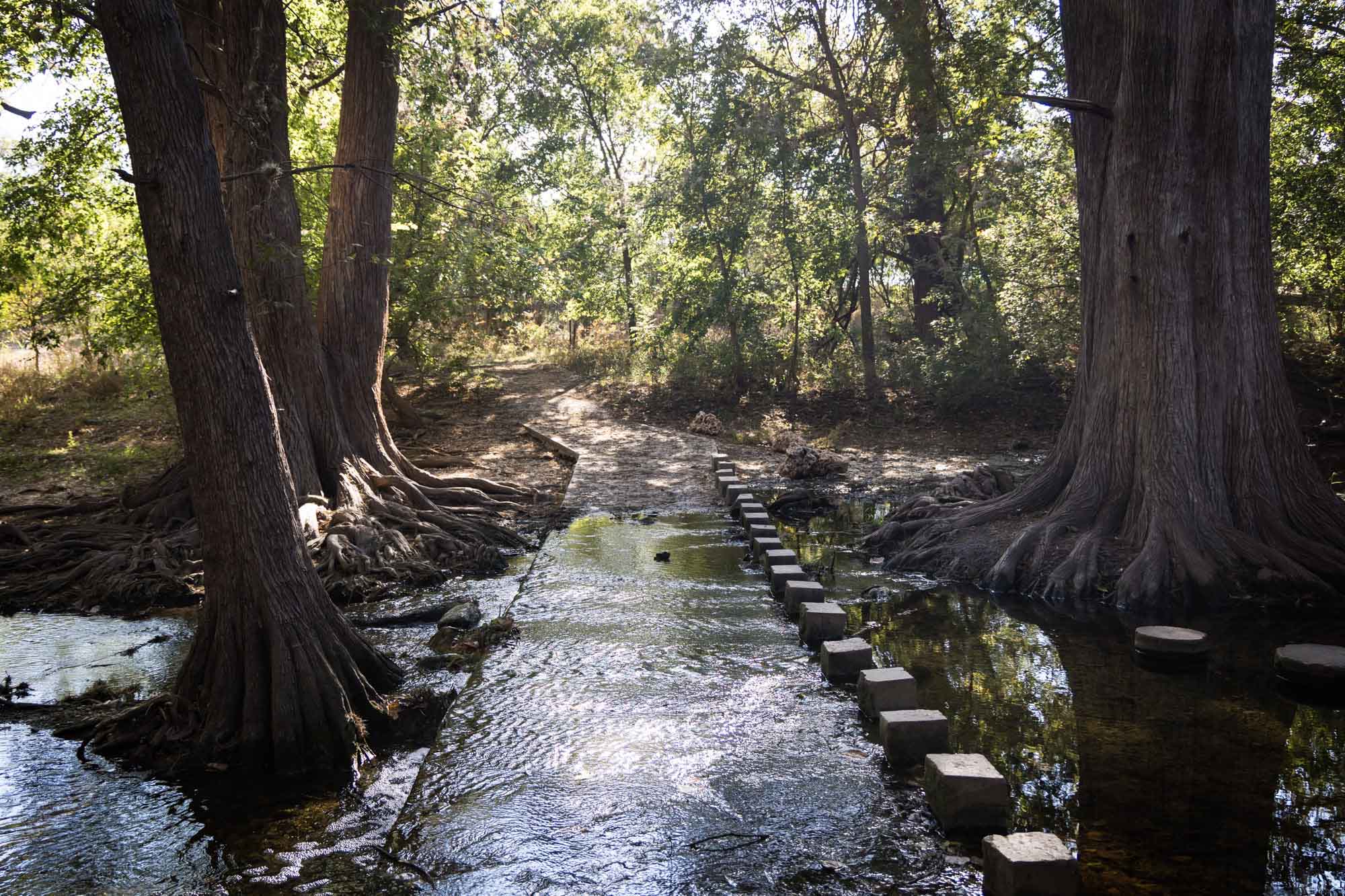 Cooper's Crossing with water flowing over concrete bridge for an article on Cibolo Nature Center surprise proposal tips