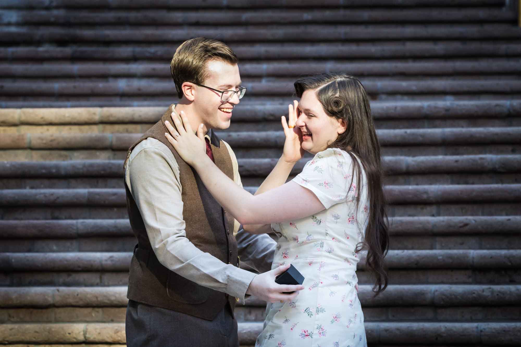 Couple hugging in front of staircase and woman wiping away tears at Weston Centre during a River Walk surprise proposal