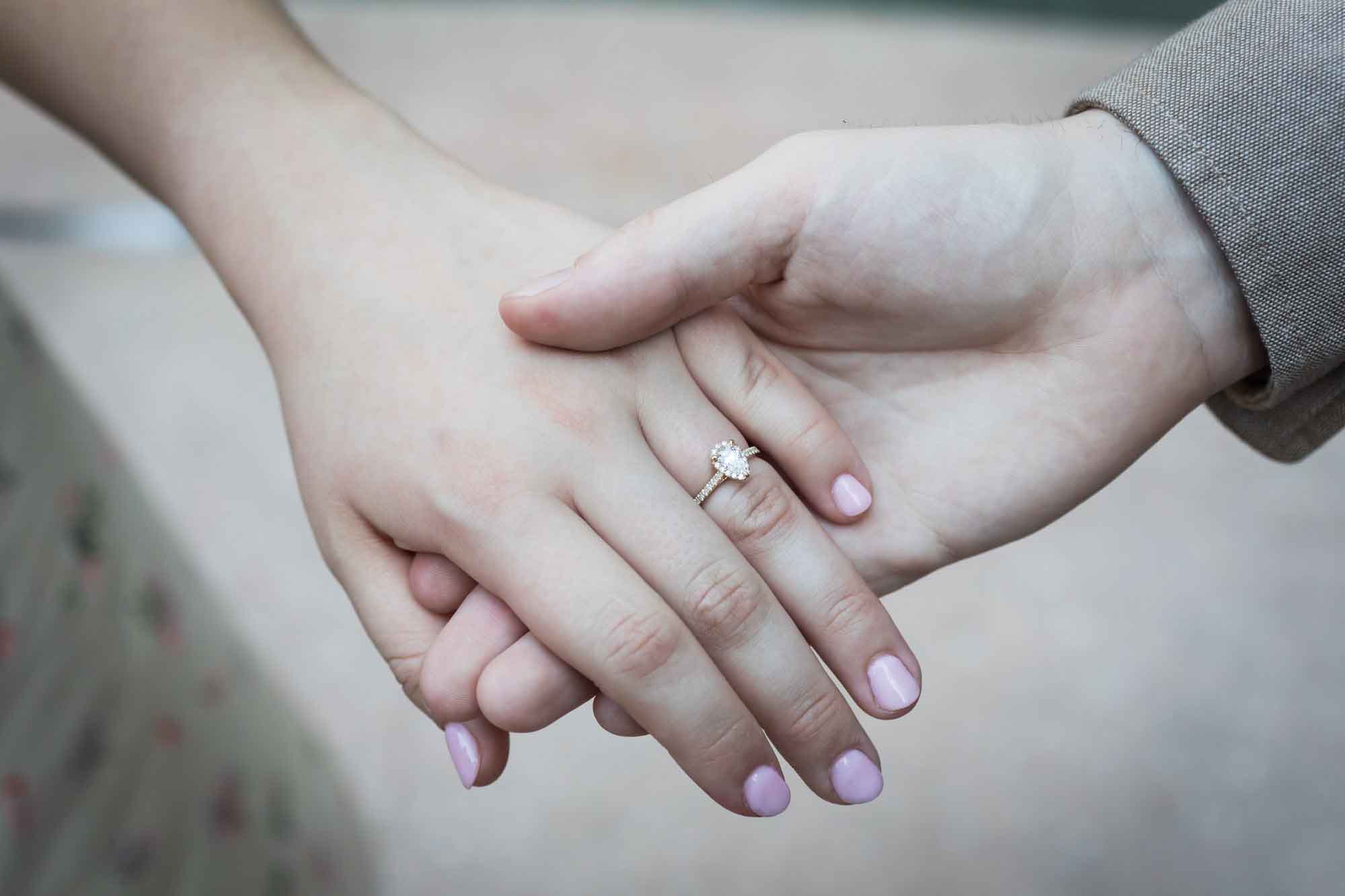Close up of man holding woman's hand showing engagement ring on her finger