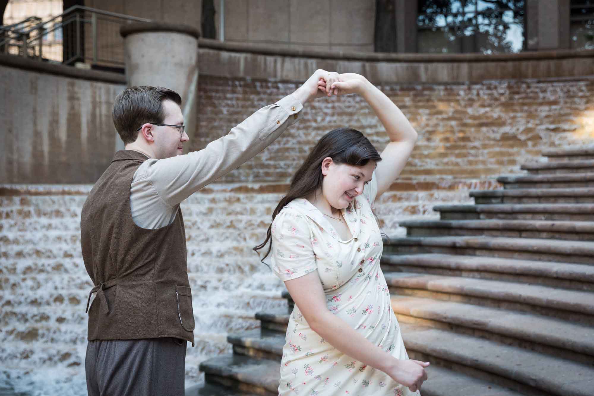 Couple dancing in front of waterfall and stairs at Weston Centre during a River Walk surprise proposal