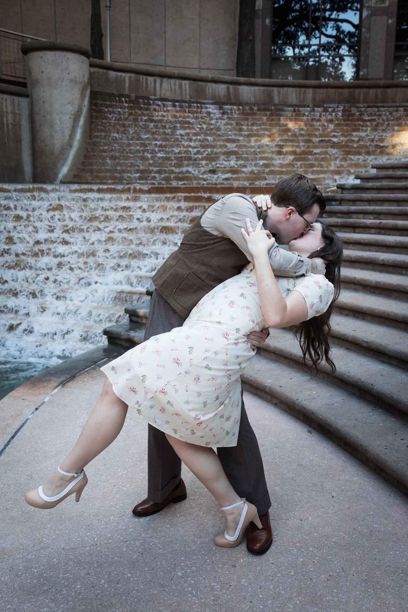 Couple kissing with dramatic dip in front of waterfall and stairs at Weston Centre during a River Walk surprise proposal