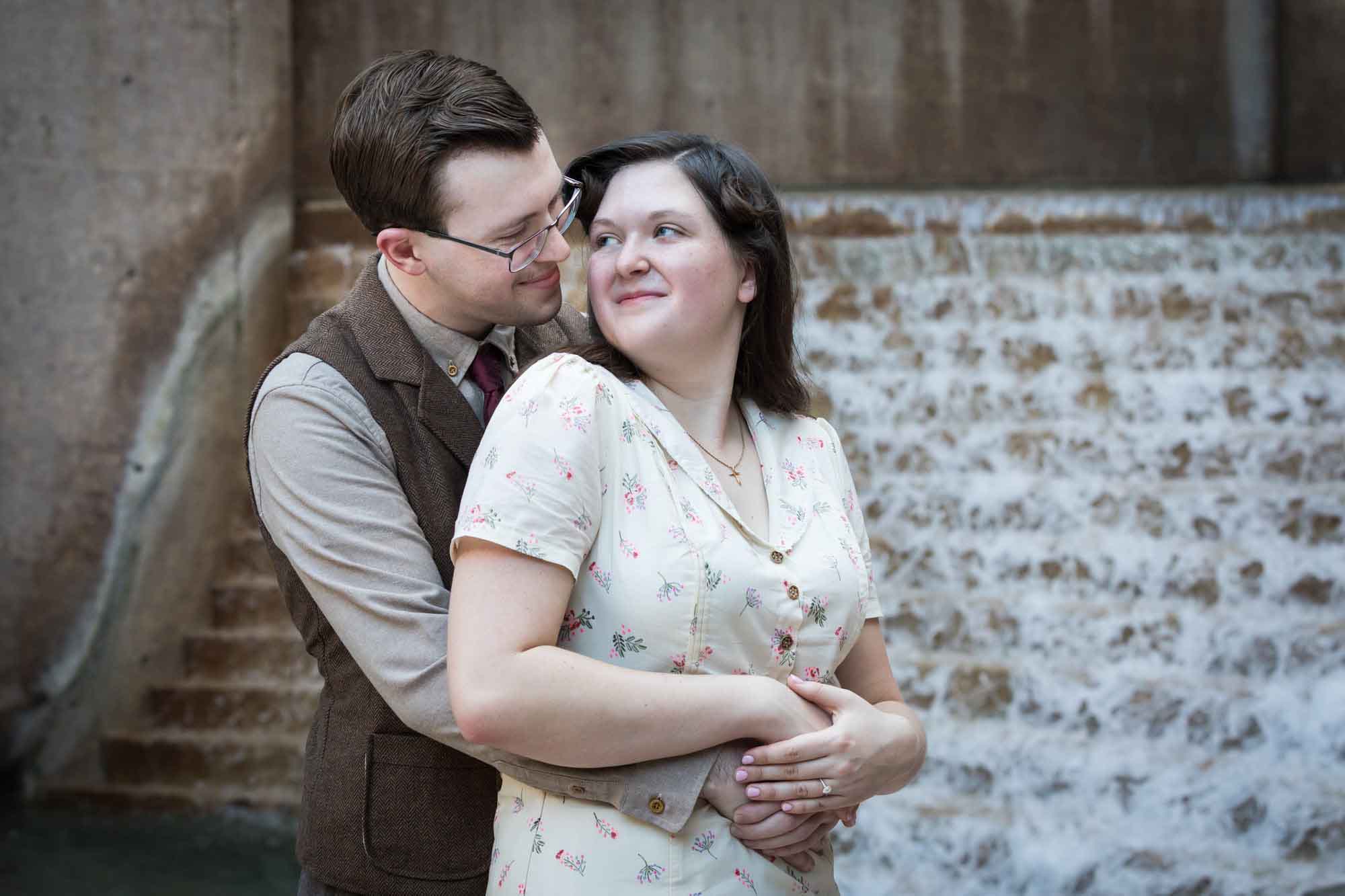Couple hugging in front of waterfall and stairs at Weston Centre during a River Walk surprise proposal
