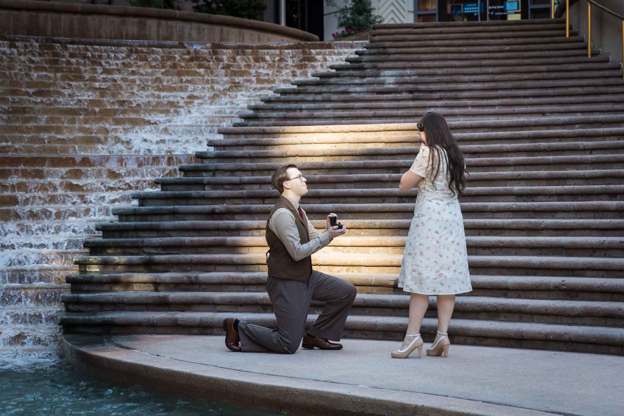 Man down on bended knee proposing to girlfriend on the Weston Centre stairs during a River Walk surprise proposal