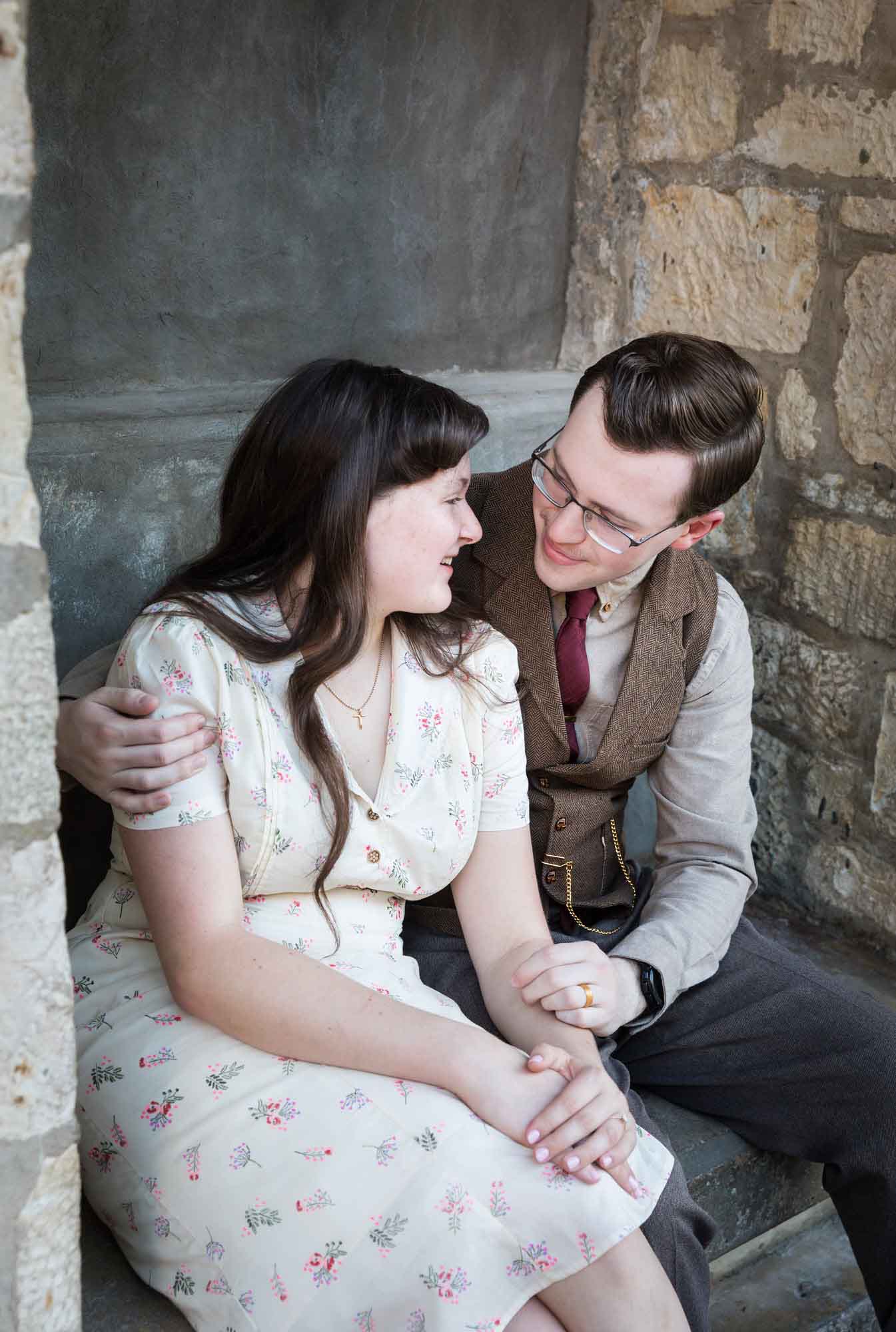 Couple hugging while seated in stone vestibule during a River Walk surprise proposal