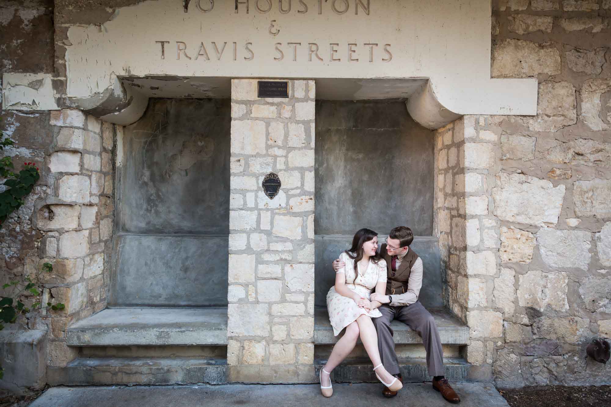 Couple seated together in stone vestibule during a River Walk surprise proposal