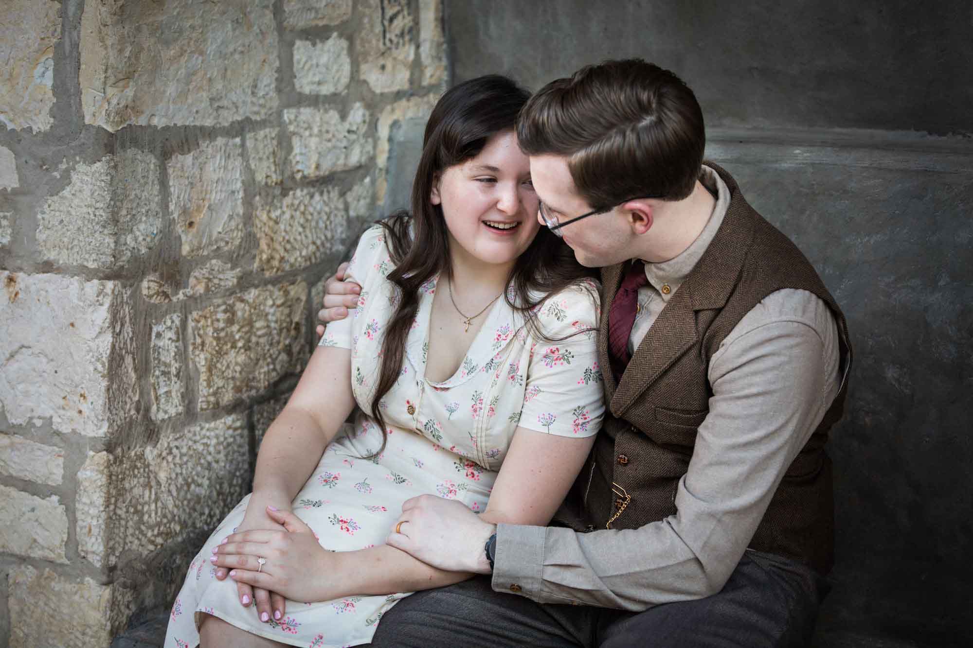 Couple hugging while seated in stone vestibule during a River Walk surprise proposal