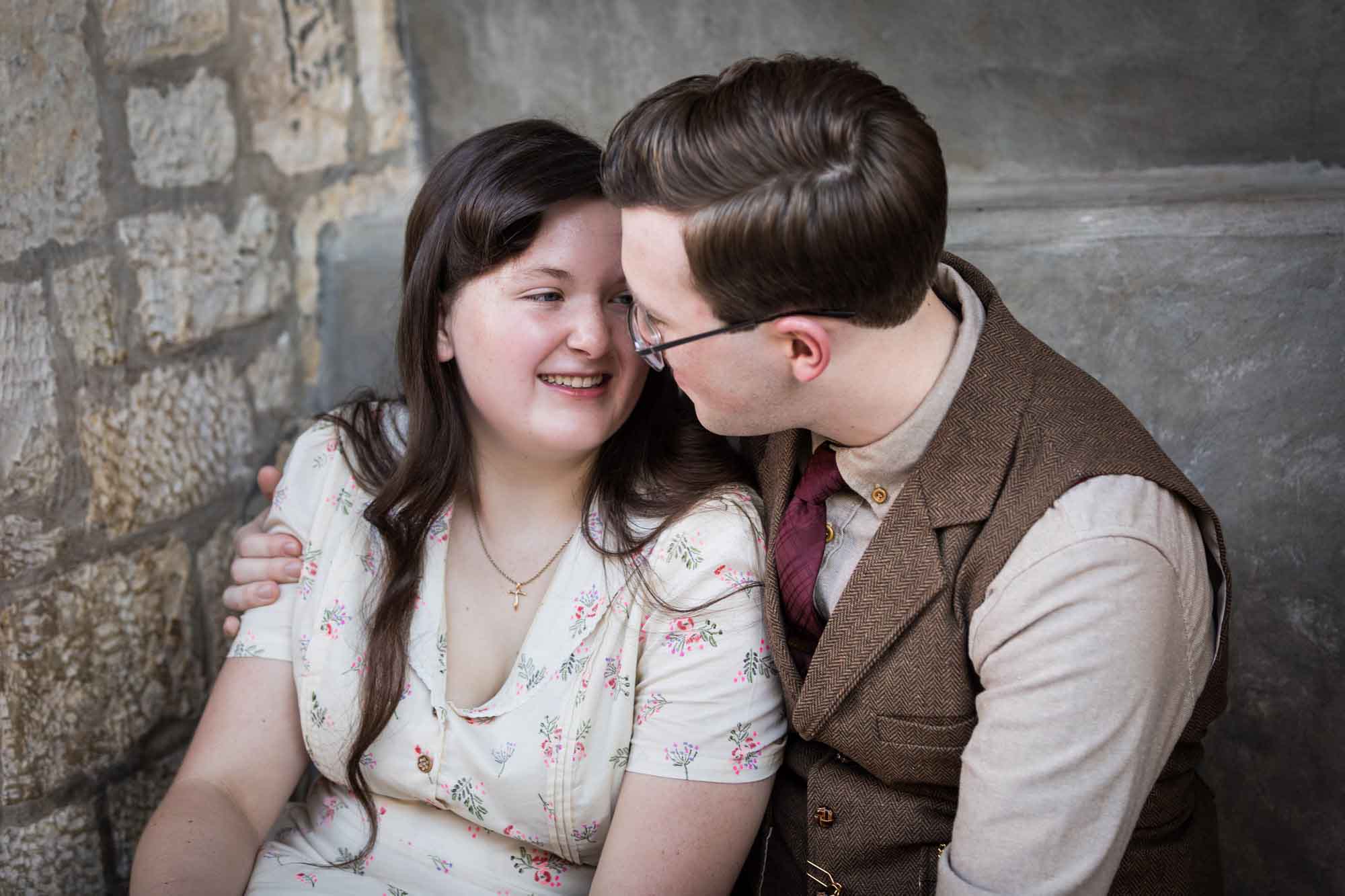 Couple hugging while seated in stone vestibule during a River Walk surprise proposal