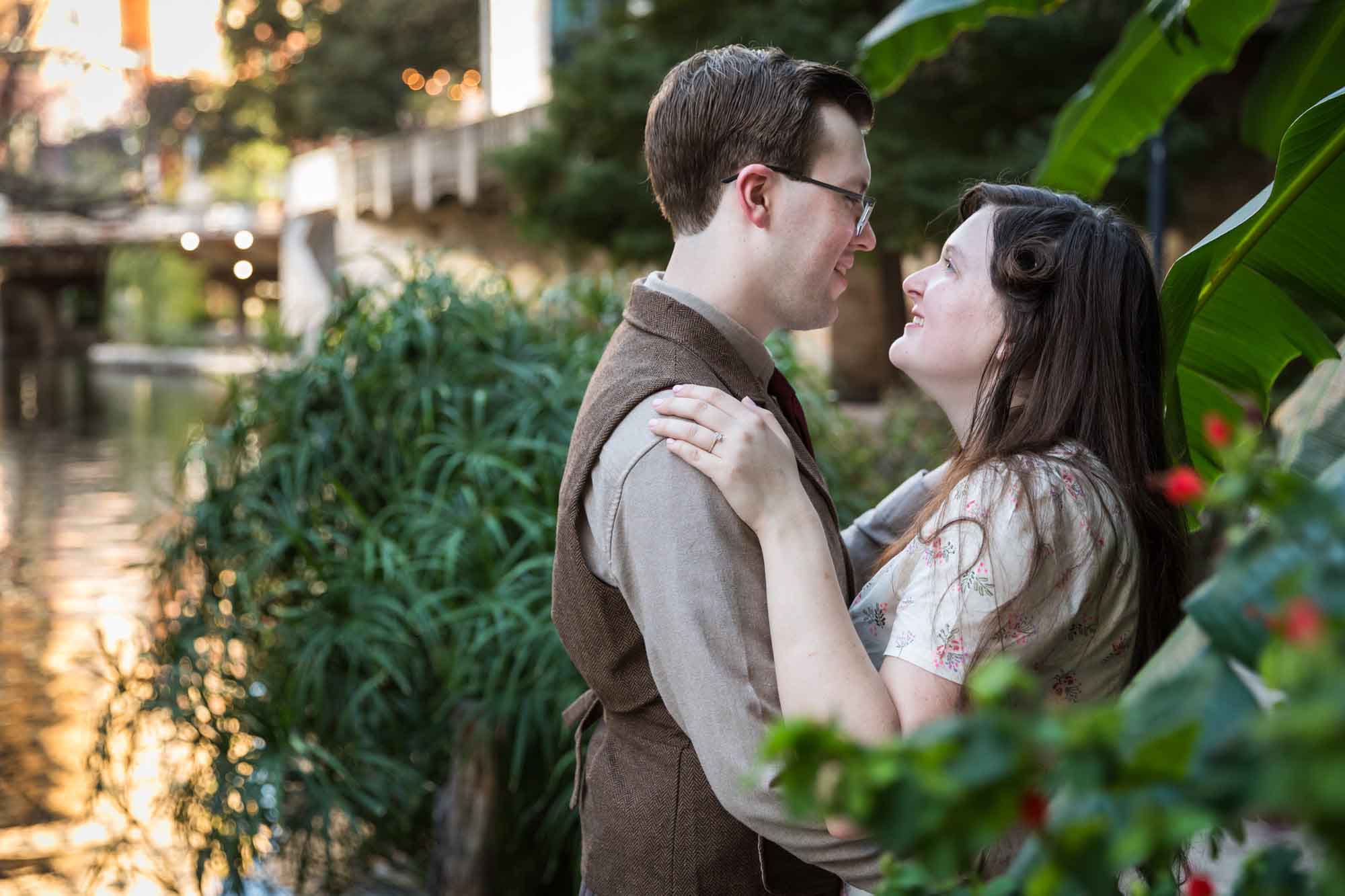 Couple hugging each other and looking at each other surrounded by plants during a River Walk surprise proposal