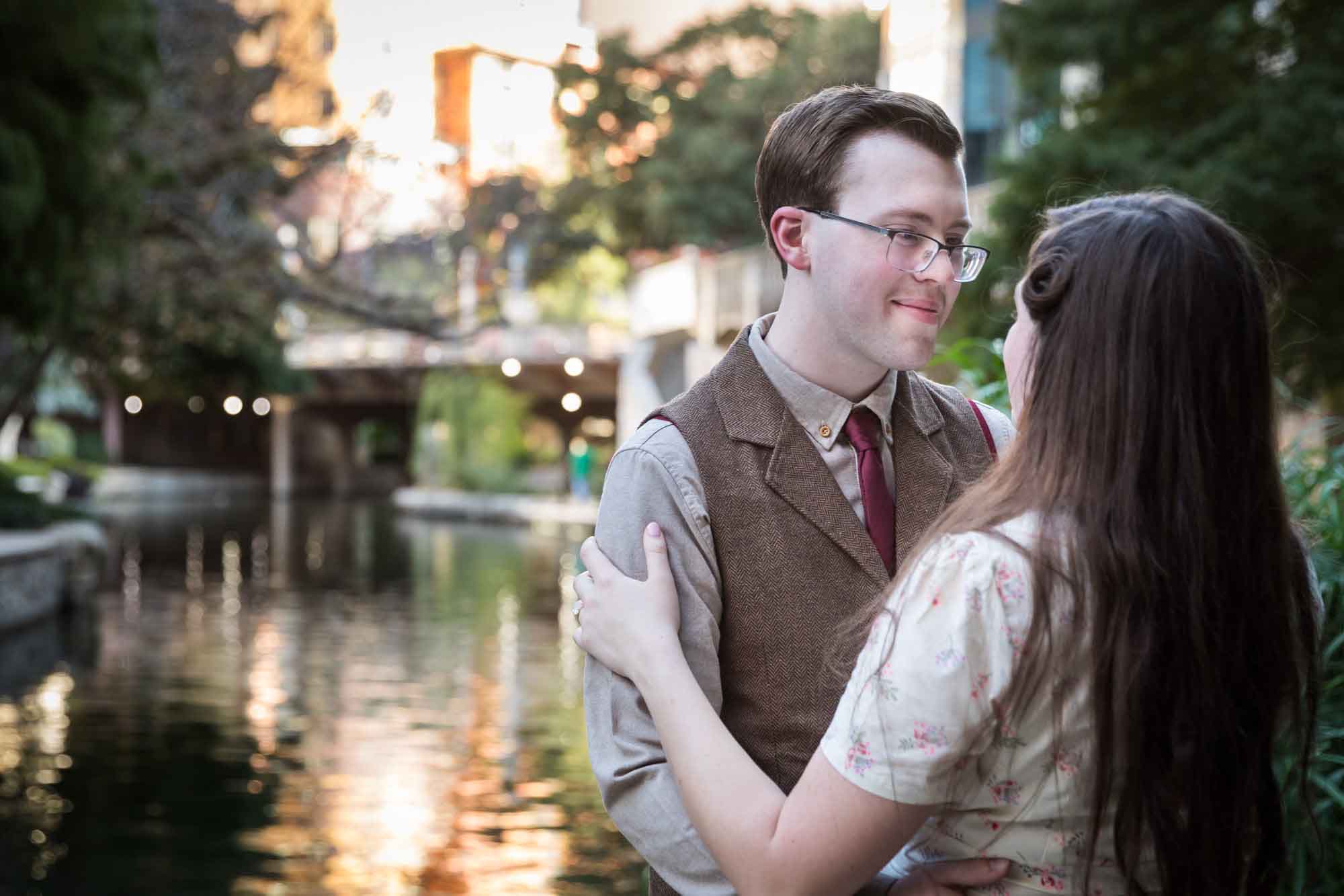 Couple hugging each other and looking at each other surrounded by plants during a River Walk surprise proposal