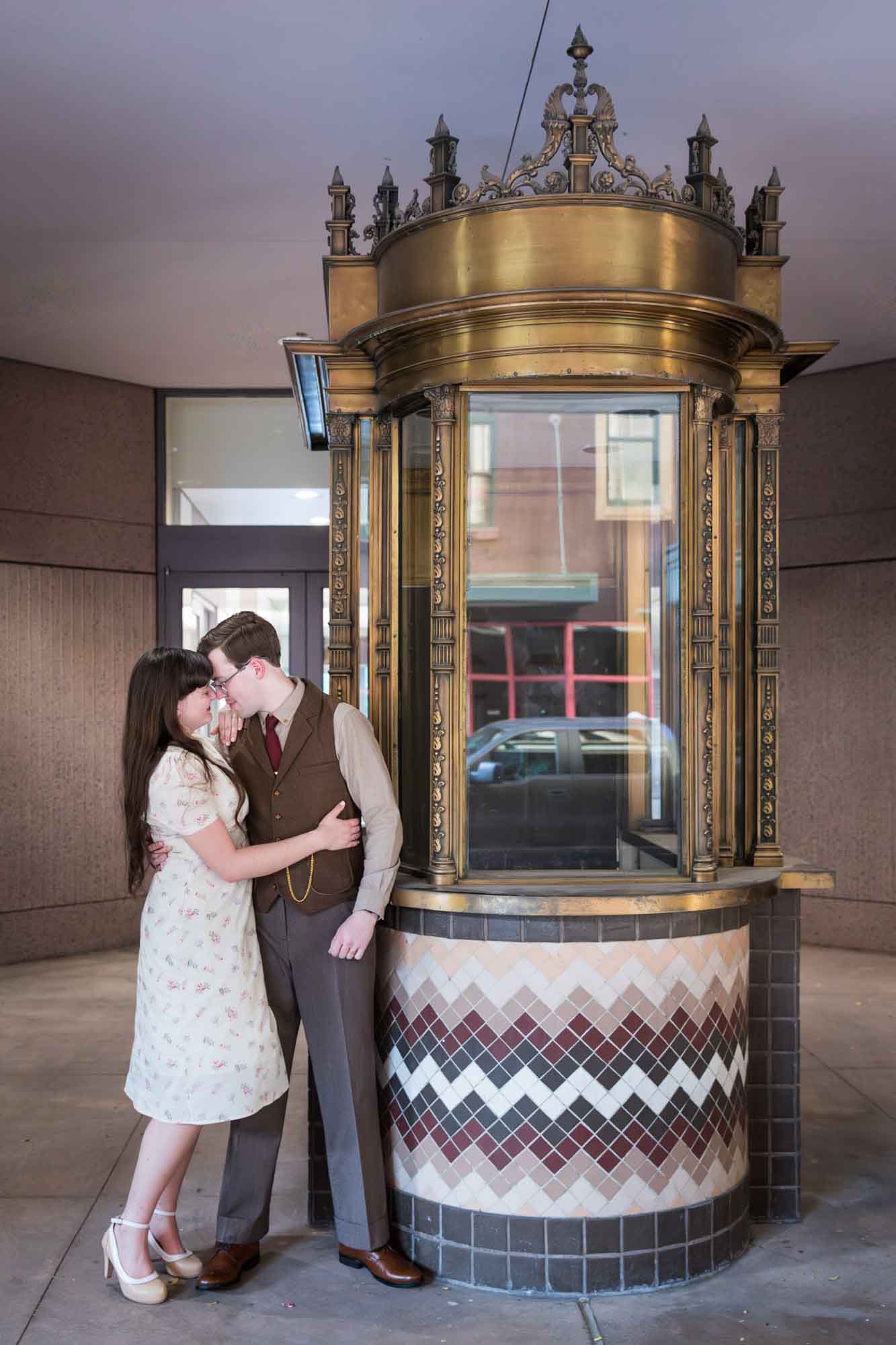 Couple hugging in front of old ticket booth during a River Walk surprise proposal