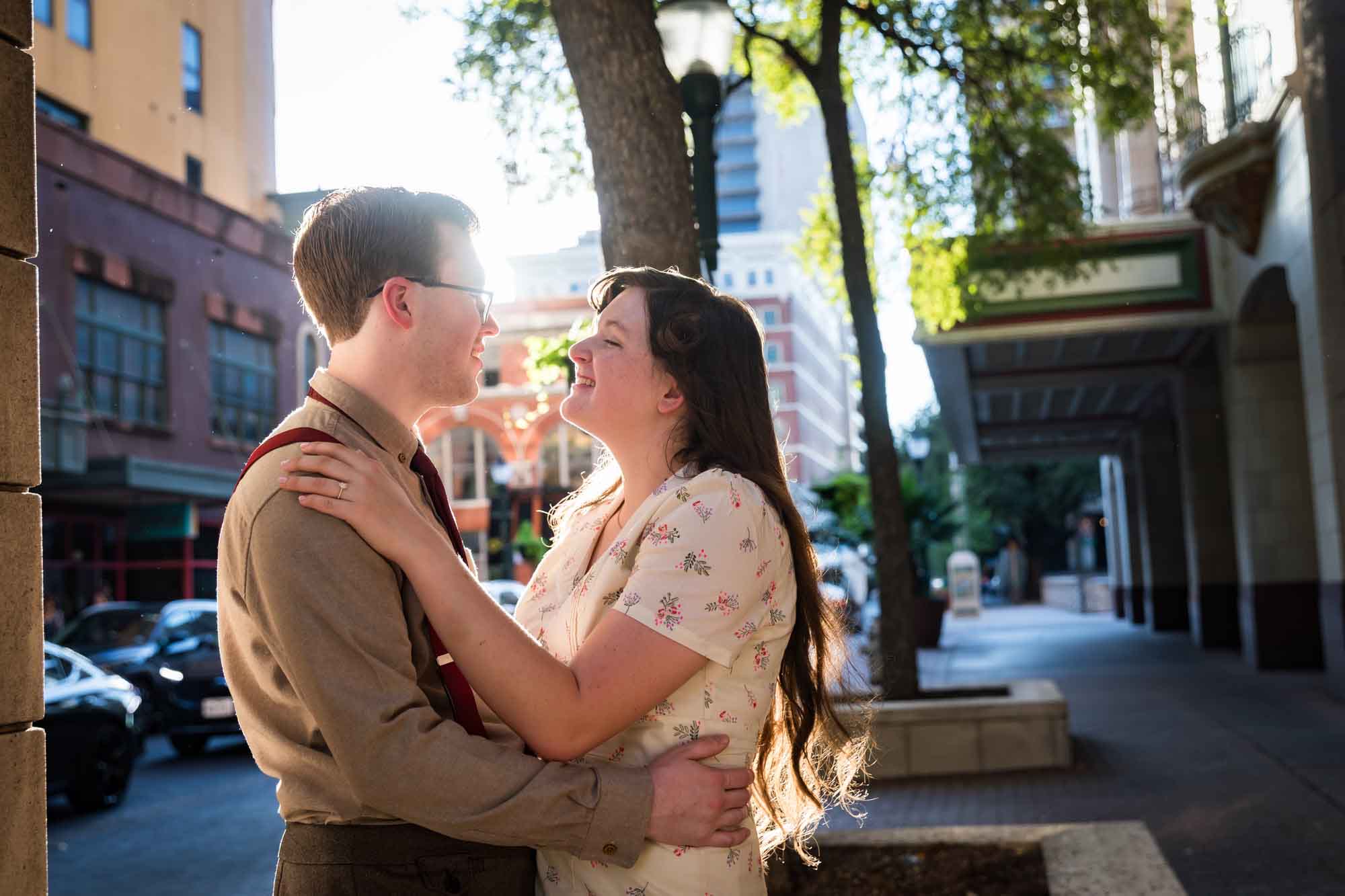 Couple hugging in the street while wearing retro outfits from the 1940s during a River Walk surprise proposal