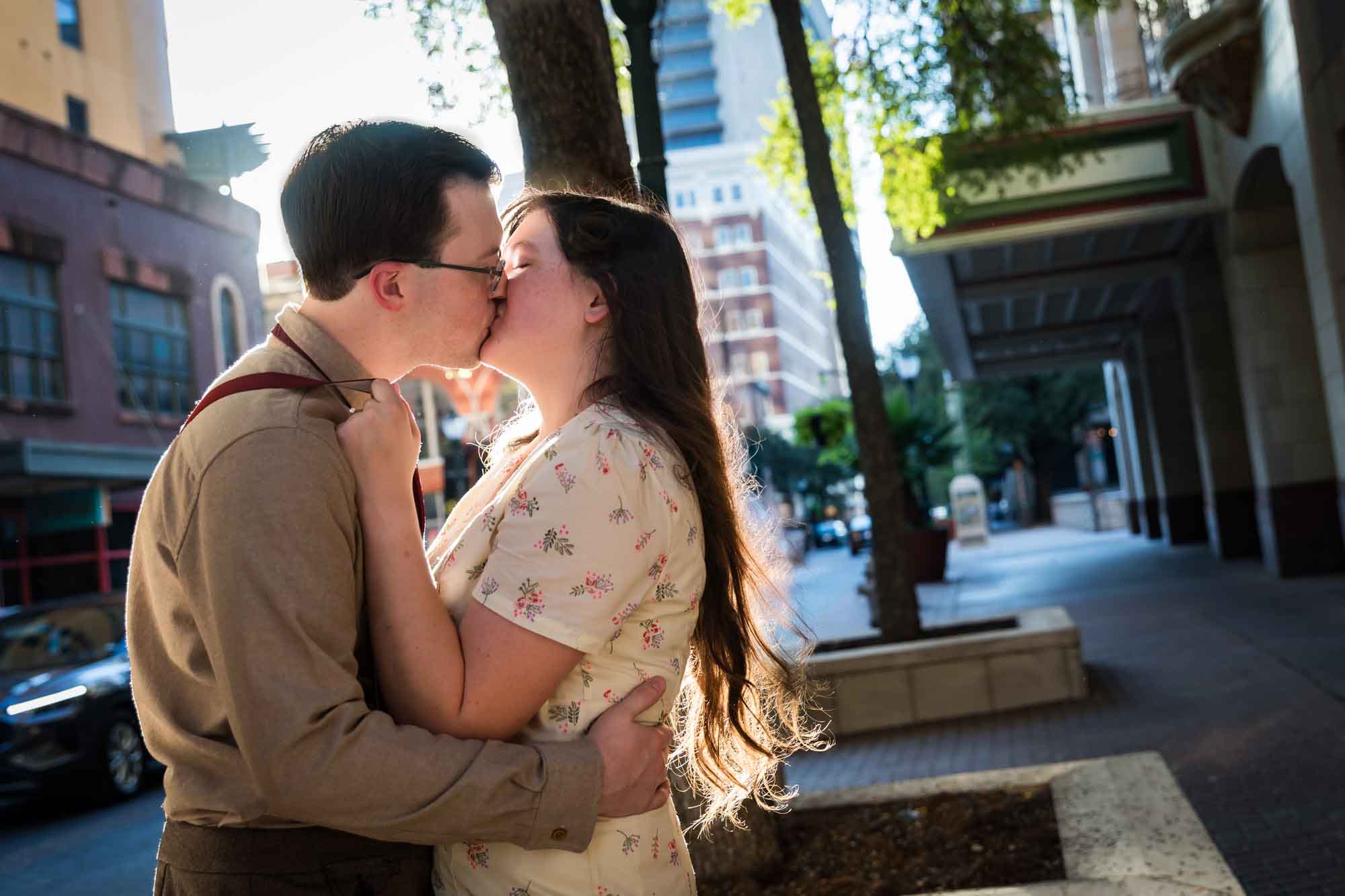 Couple kissing in the street while wearing retro outfits from the 1940s during a River Walk surprise proposal