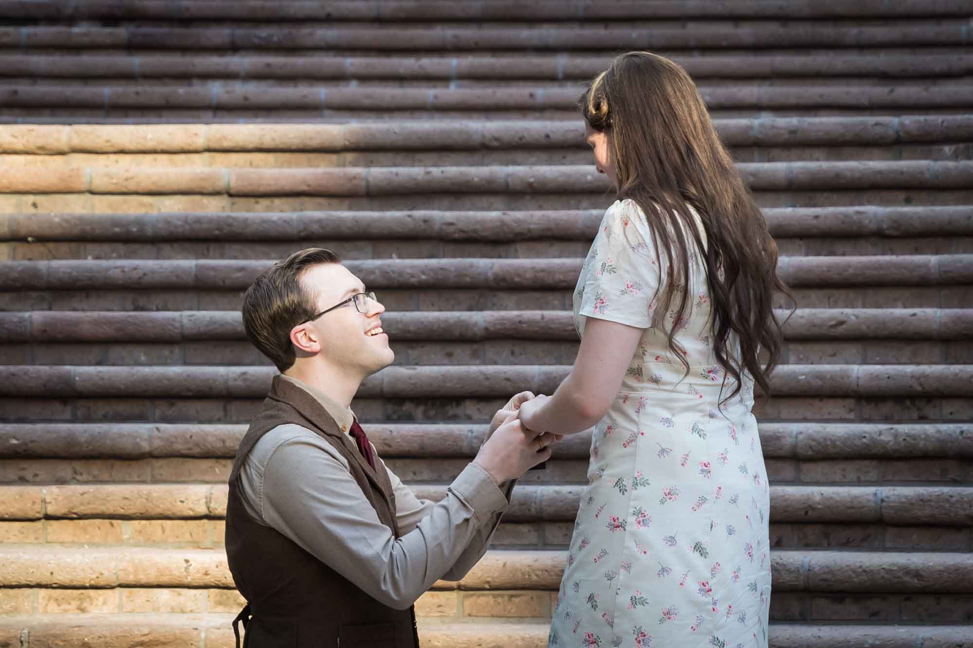 Man down on bended knee proposing to girlfriend on the Weston Centre stairs during a River Walk surprise proposal