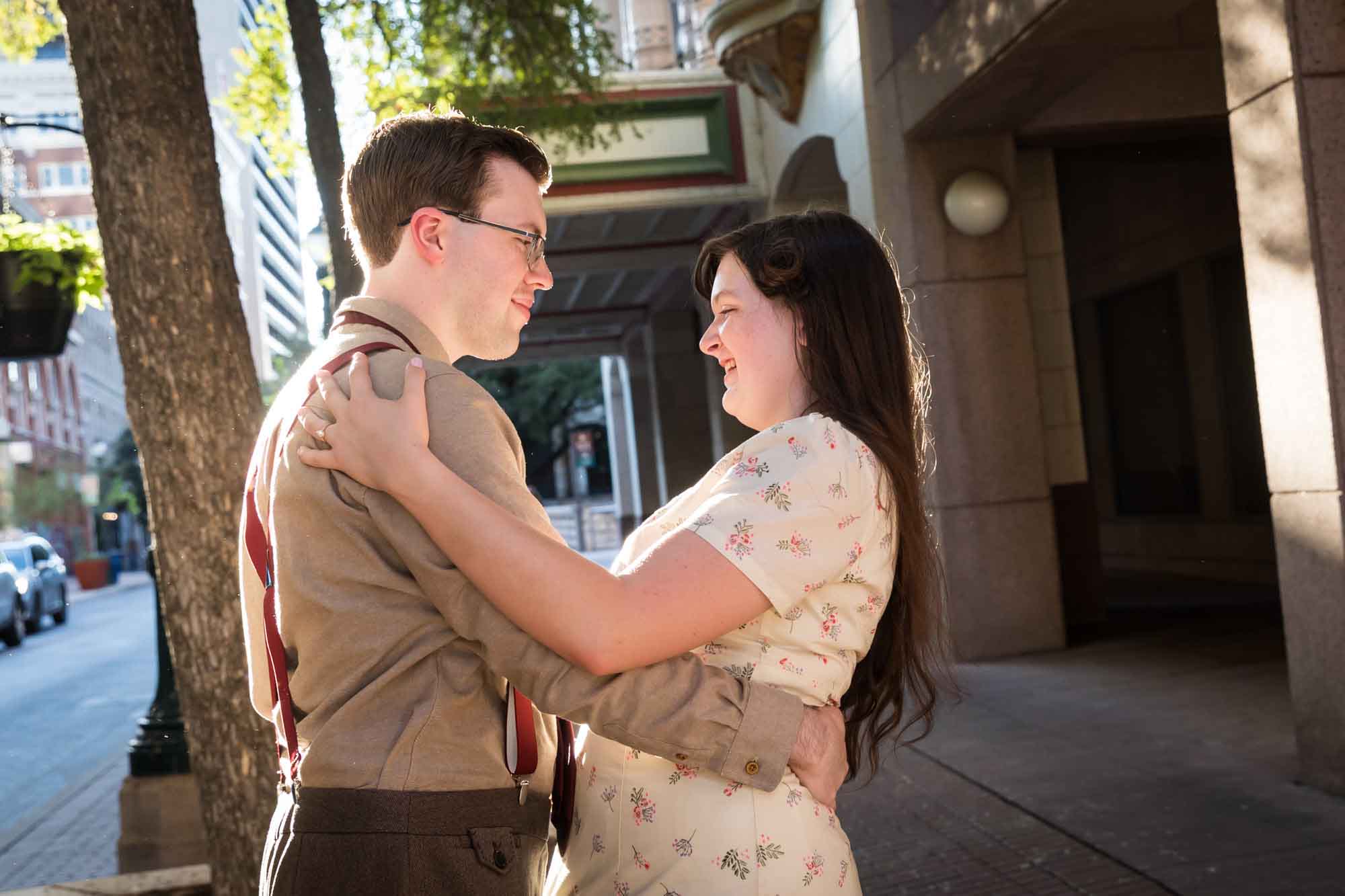 Couple hugging in the street while wearing retro outfits from the 1940s during a River Walk surprise proposal