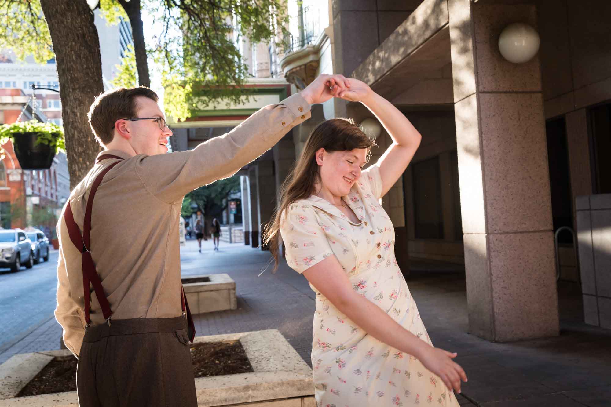 Couple dancing in the street while wearing retro outfits from the 1940s during a River Walk surprise proposal
