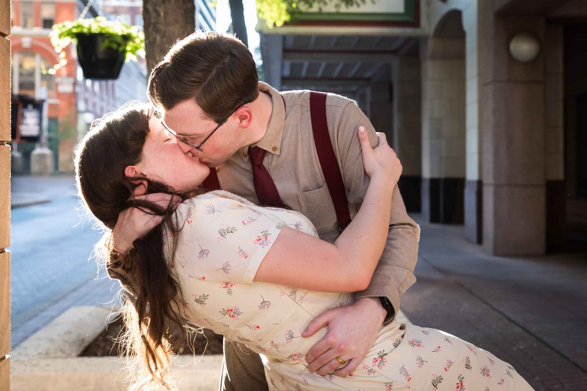 Man kissing woman in the street while wearing retro outfits from the 1940s during a River Walk surprise proposal