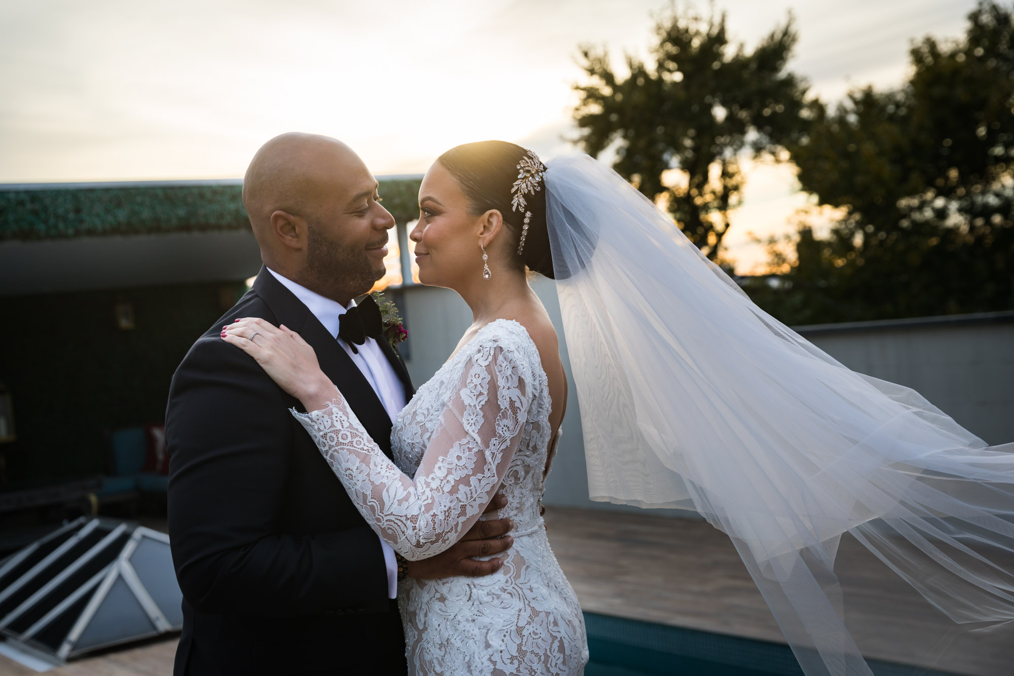 Bride and groom looking at each other on roof at sunset for an article on unexpected wedding photo tips