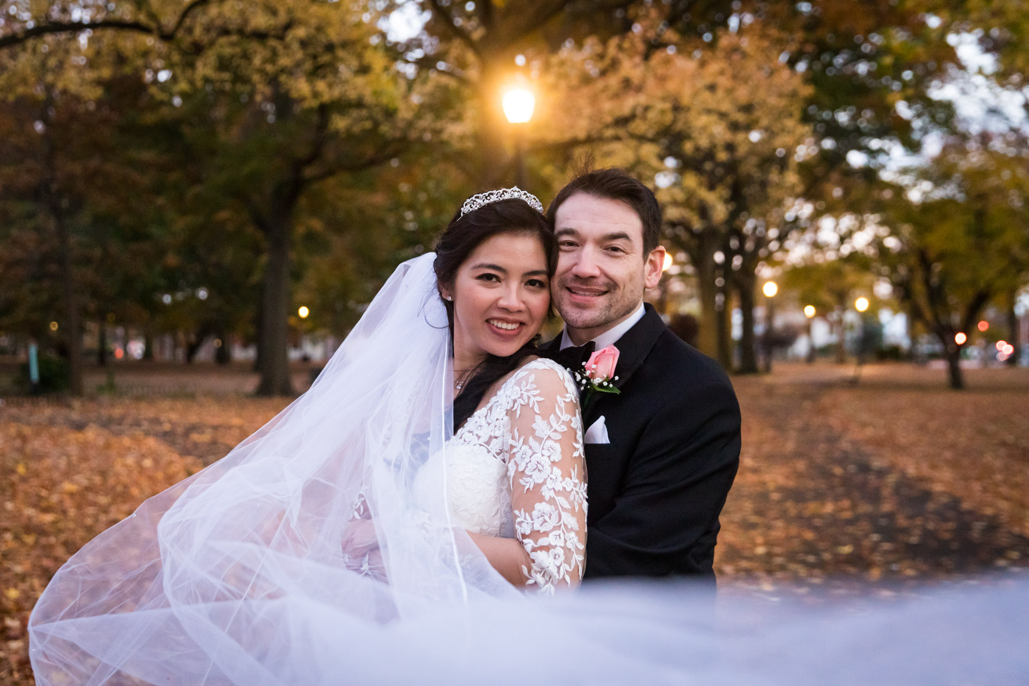 Bride and groom hugging with veil flowing in front of couple and fall forest in background for an article on unexpected wedding photo tips