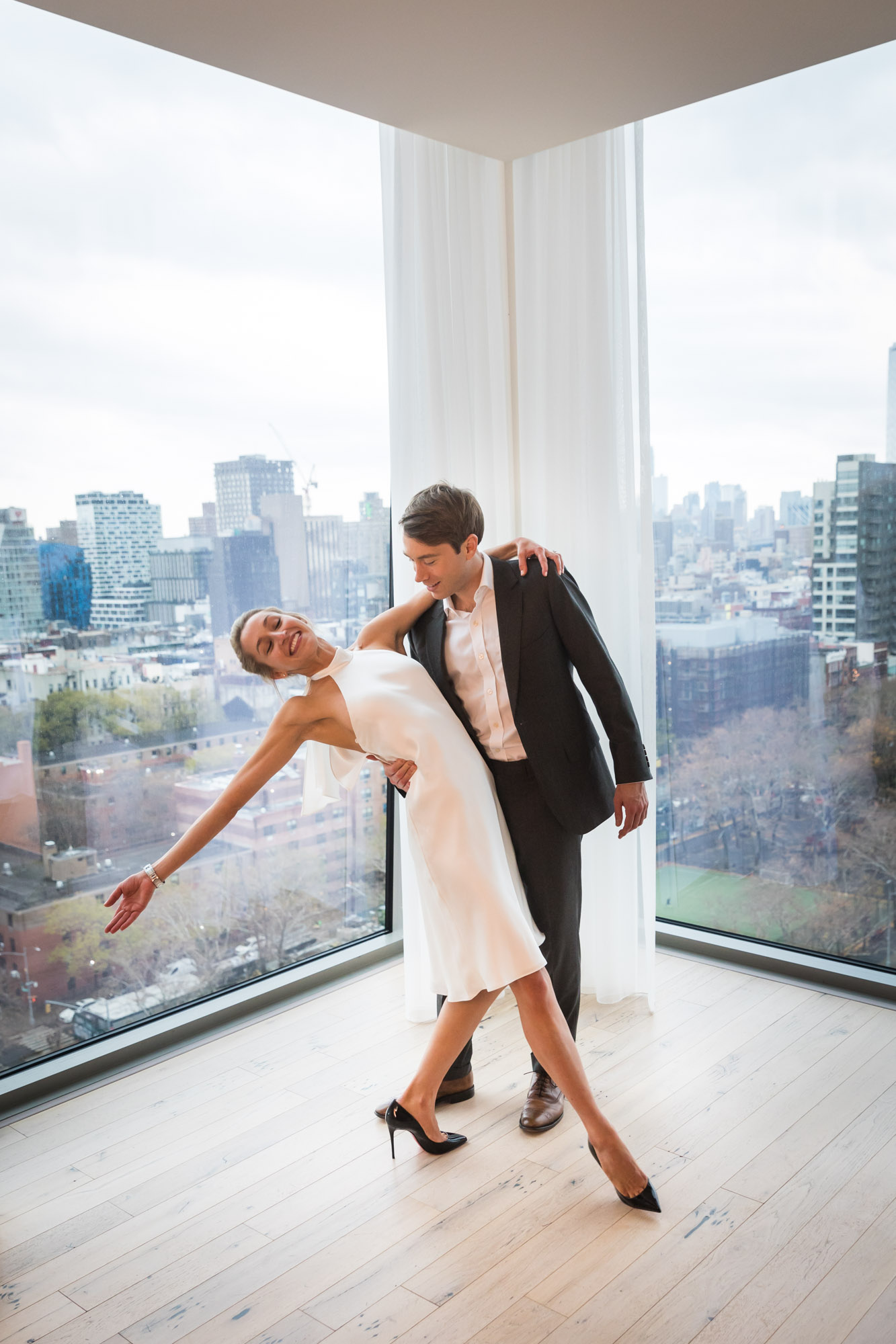 Groom dipping bride in front of windows with city skyline in background for an article on unexpected wedding photo tips