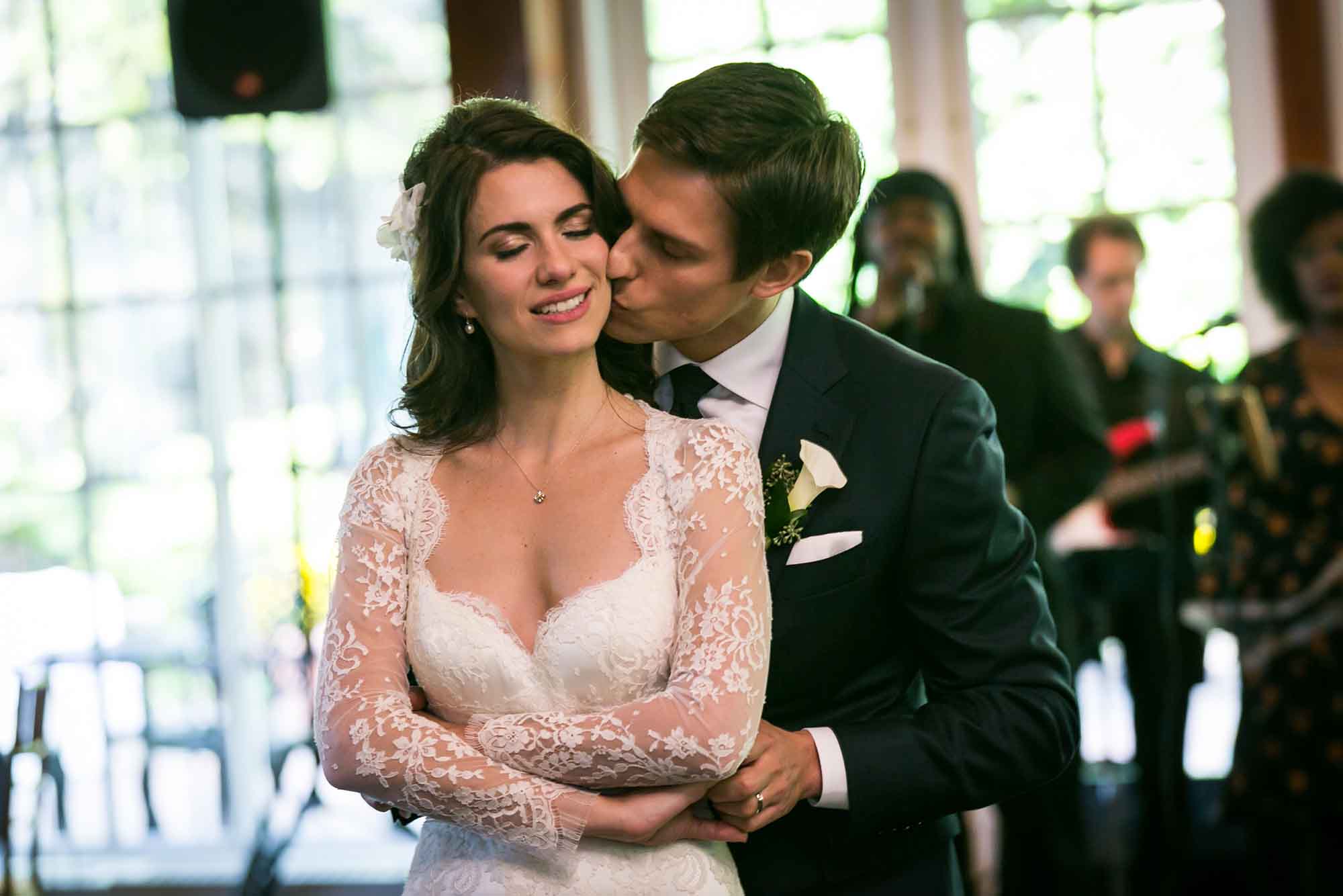 Groom kissing bride on the cheek while dancing for an article on unexpected wedding photo tips