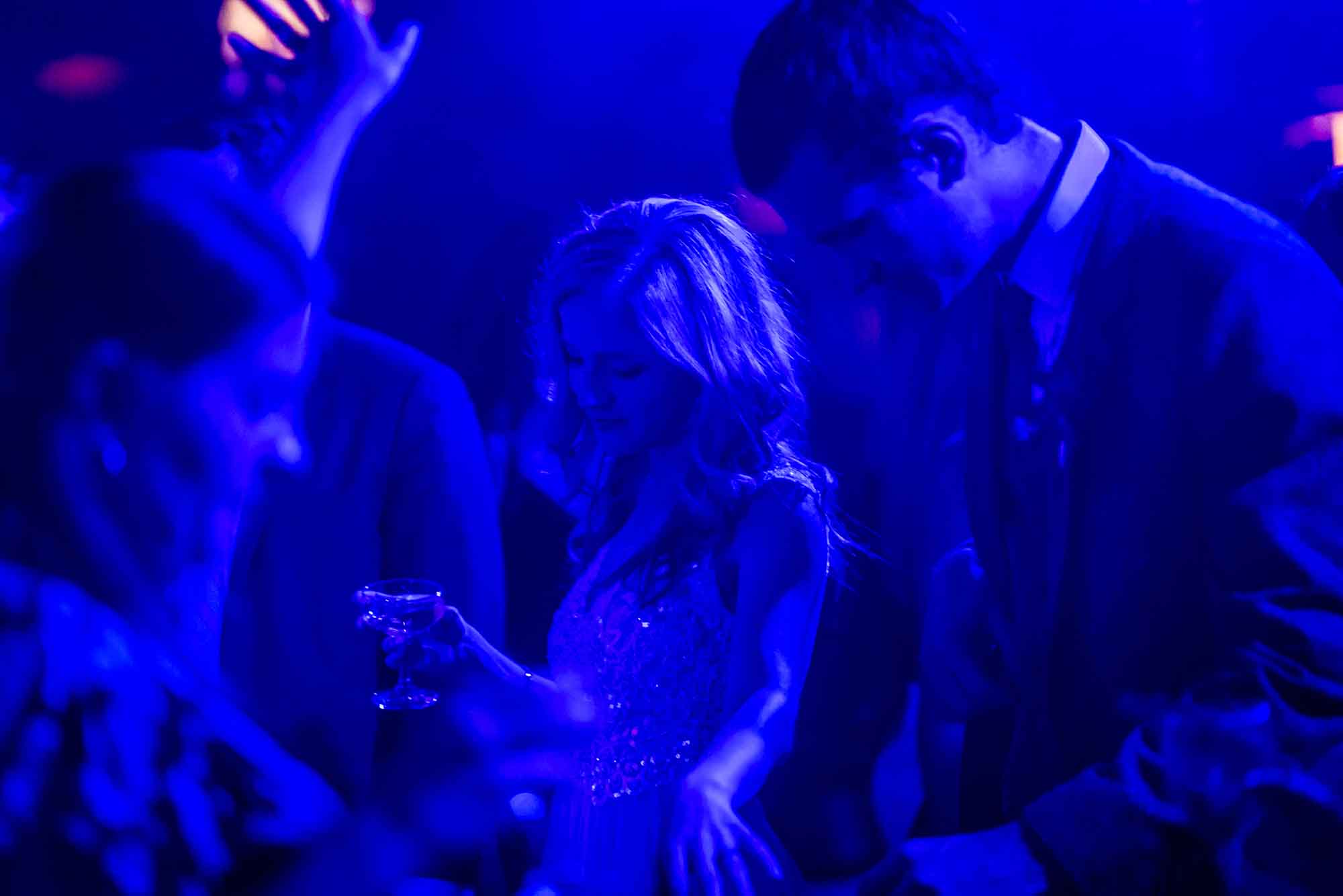 Bride dancing with guests lit with blue light for an article on unexpected wedding photo tips