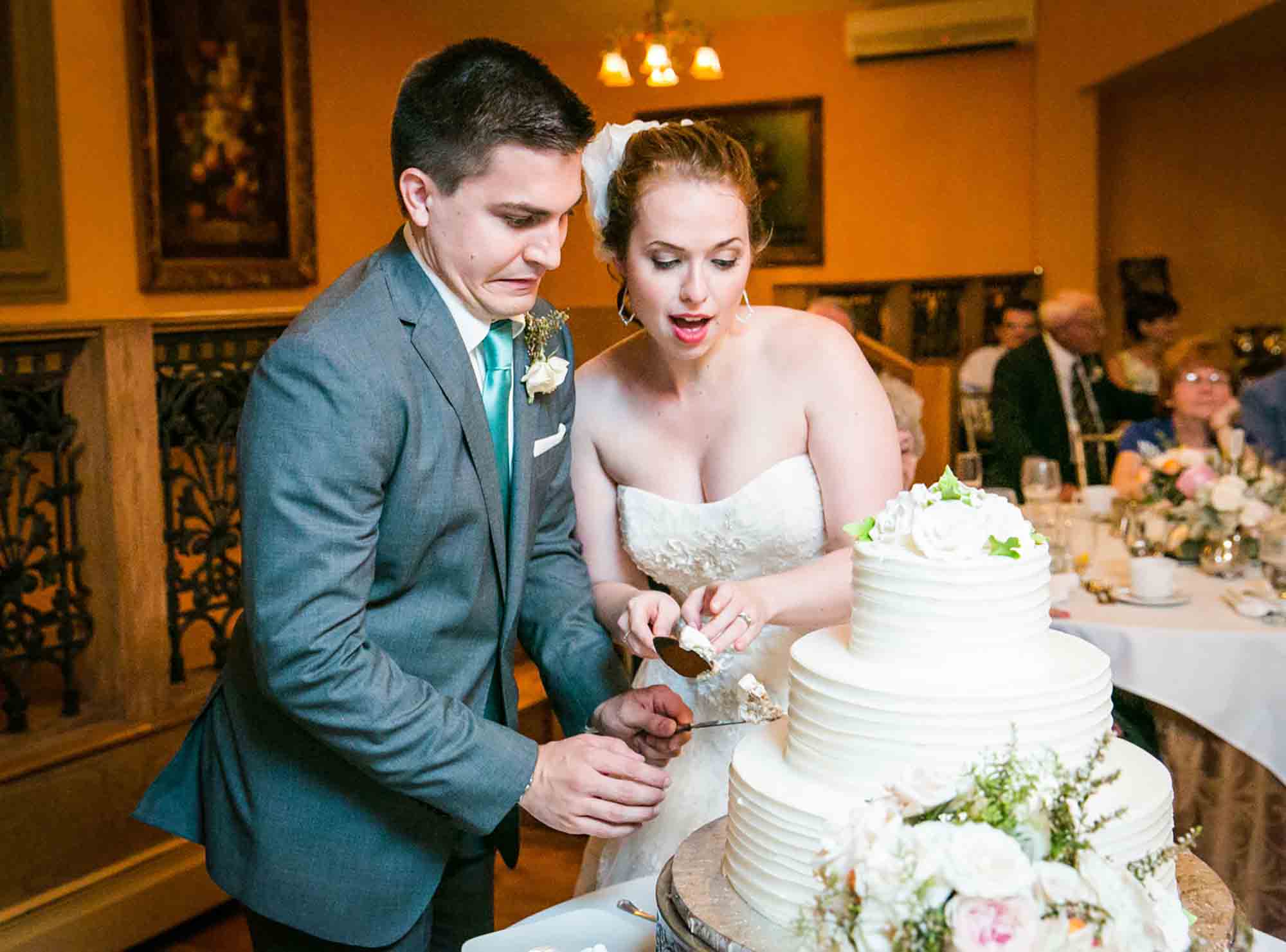 Bride and groom cutting cake in front of guests for an article on unexpected wedding photo tips