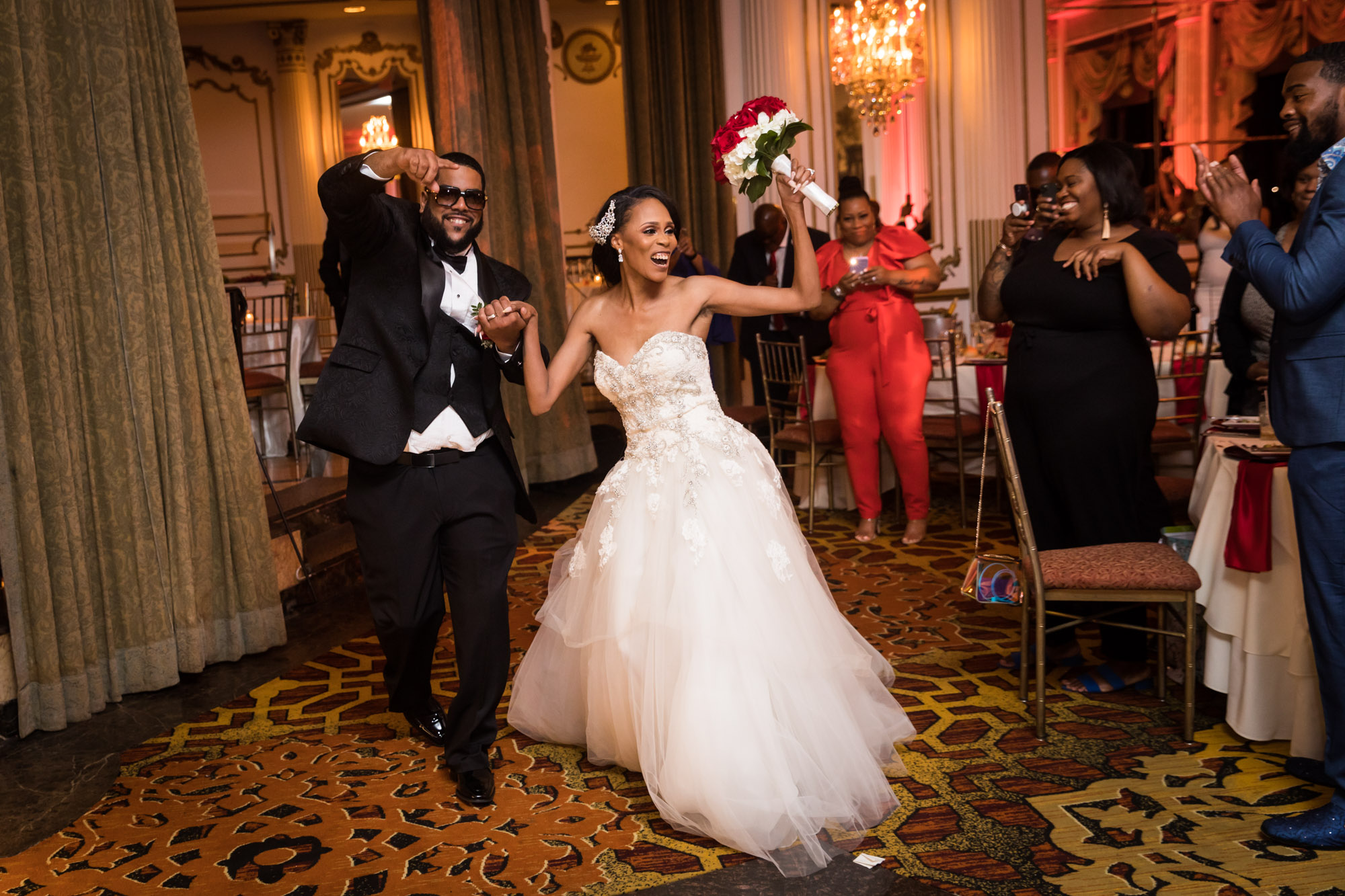 African American bride and groom entering reception room with guests cheering for an article on unexpected wedding photo tips