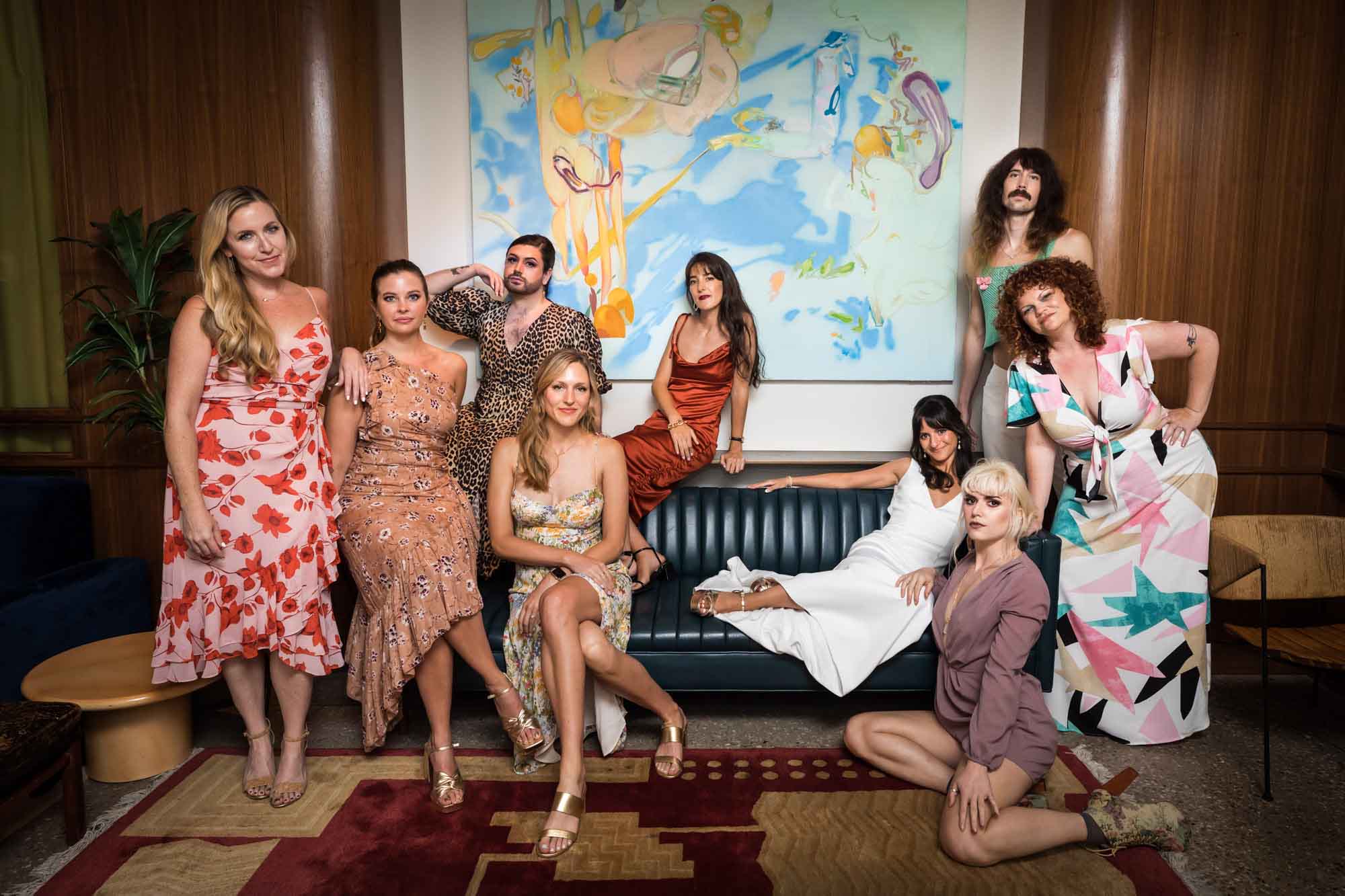 Bride and guests lounging on furniture for stylish portrait in front of painting for an article on unexpected wedding photo tips